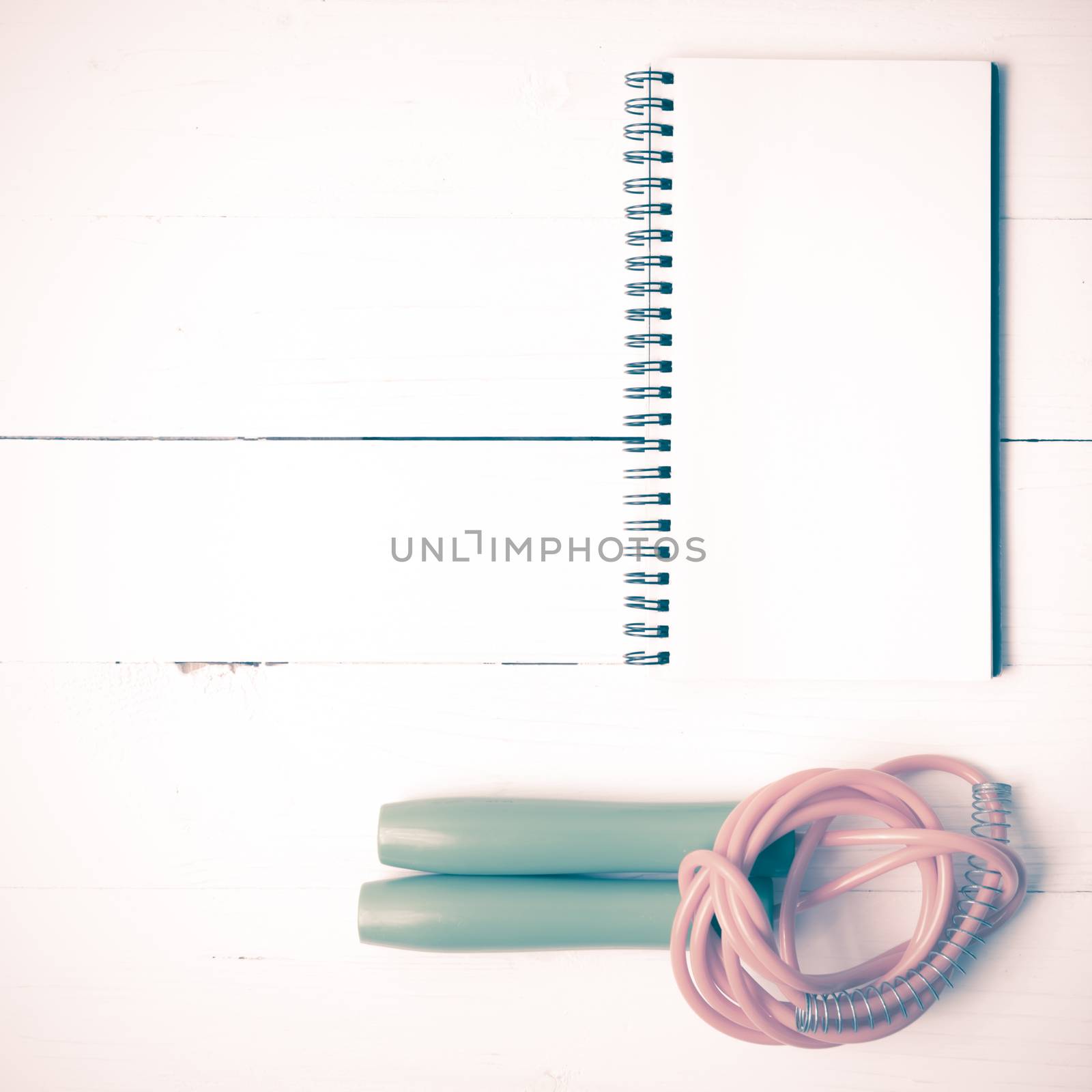 fitness equipment : jumping rope and notepad on white wood table vintage style