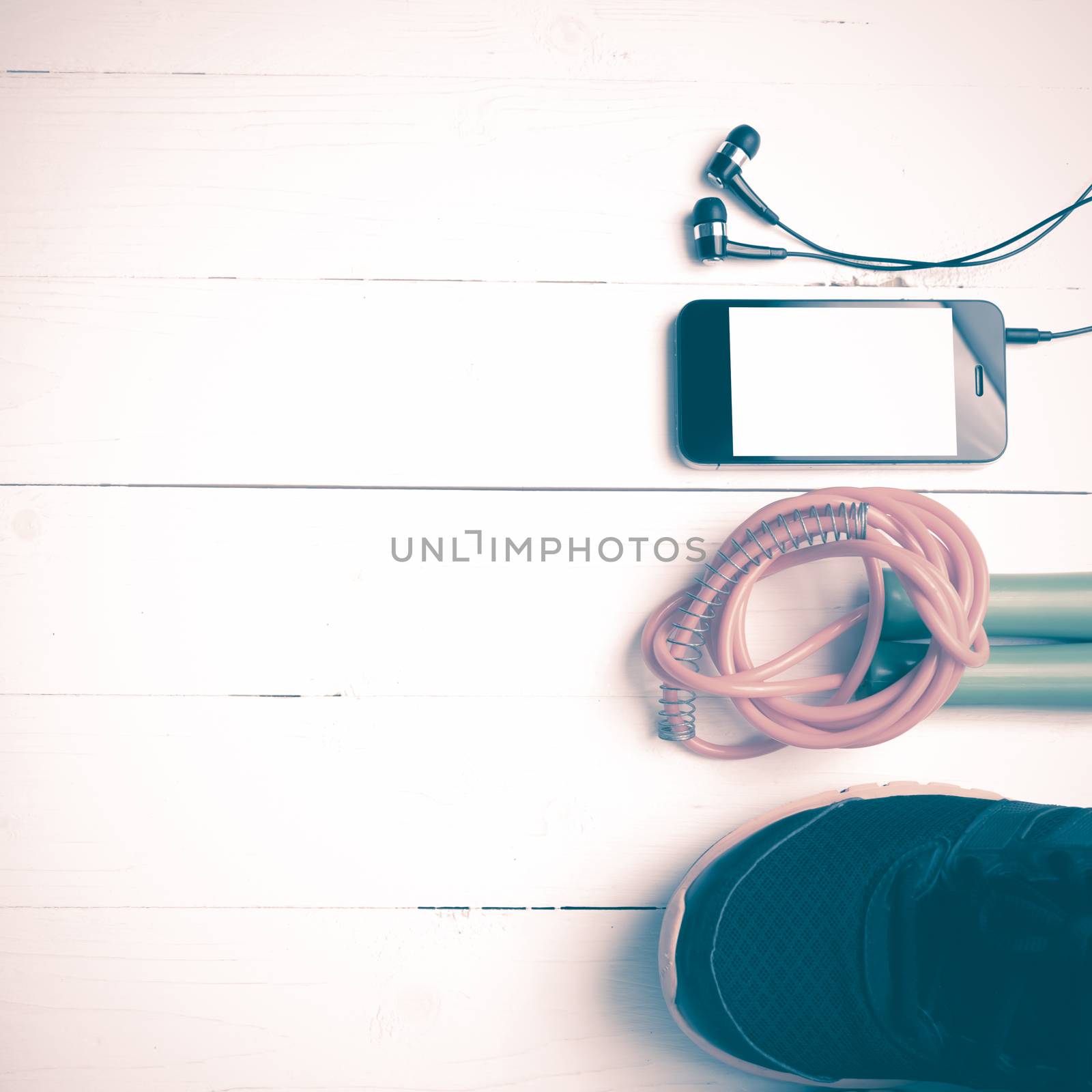 fitness equipment : running shoes,jumping rope and phone on white wood table vintage style