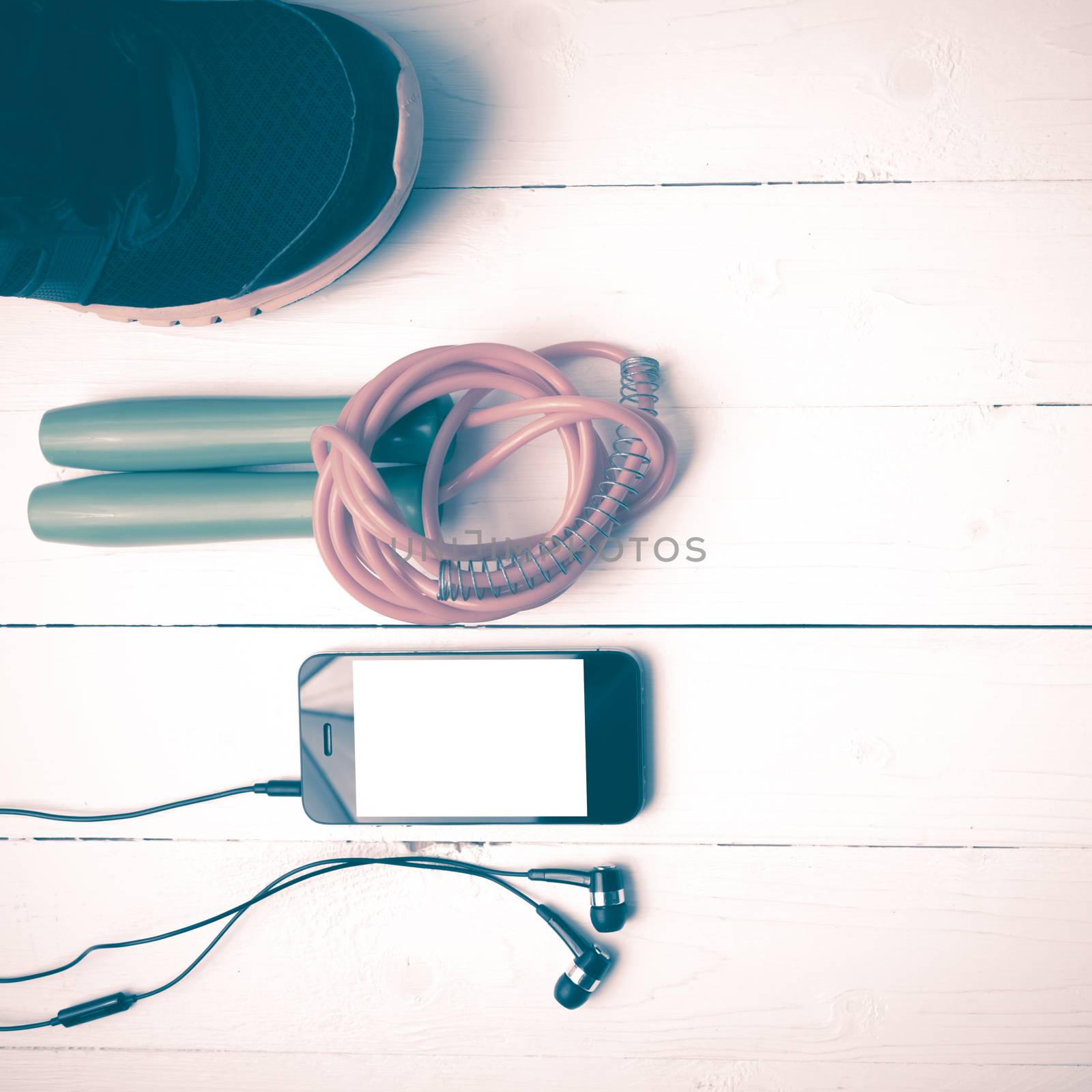 fitness equipment : running shoes,jumping rope and phone on white wood table vintage style