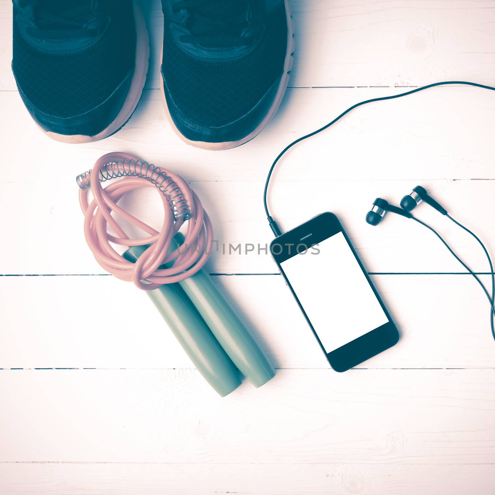 fitness equipment : running shoes,jumping rope and phone on white wood table vintage style