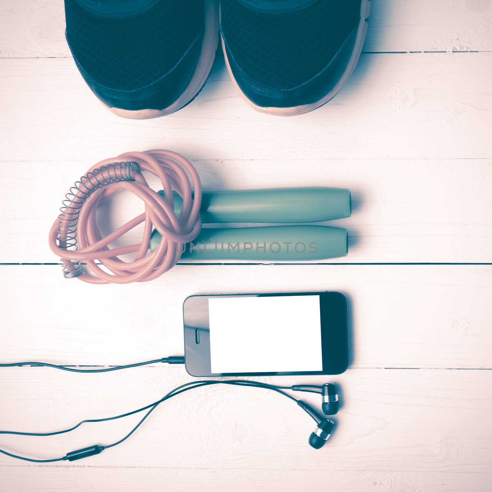 fitness equipment : running shoes,jumping rope and phone on white wood table vintage style