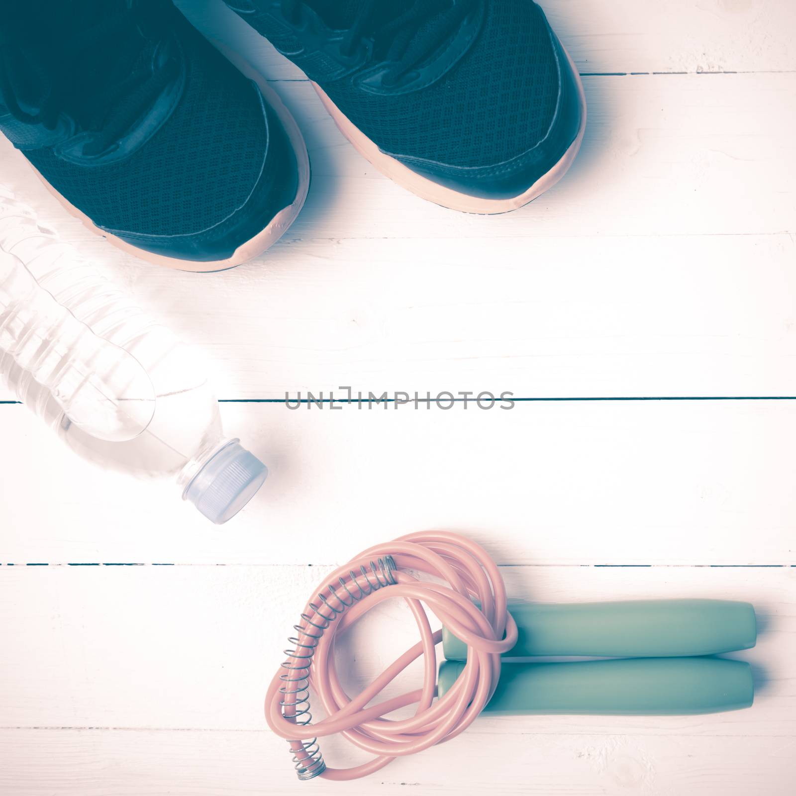 fitness equipment : running shoes,jumping rope, and water bottle on white wood table vintage style