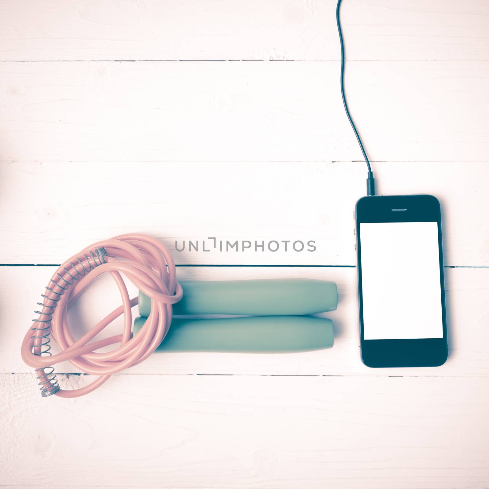 fitness equipment : jumping rope and phone on white wood table vintage style