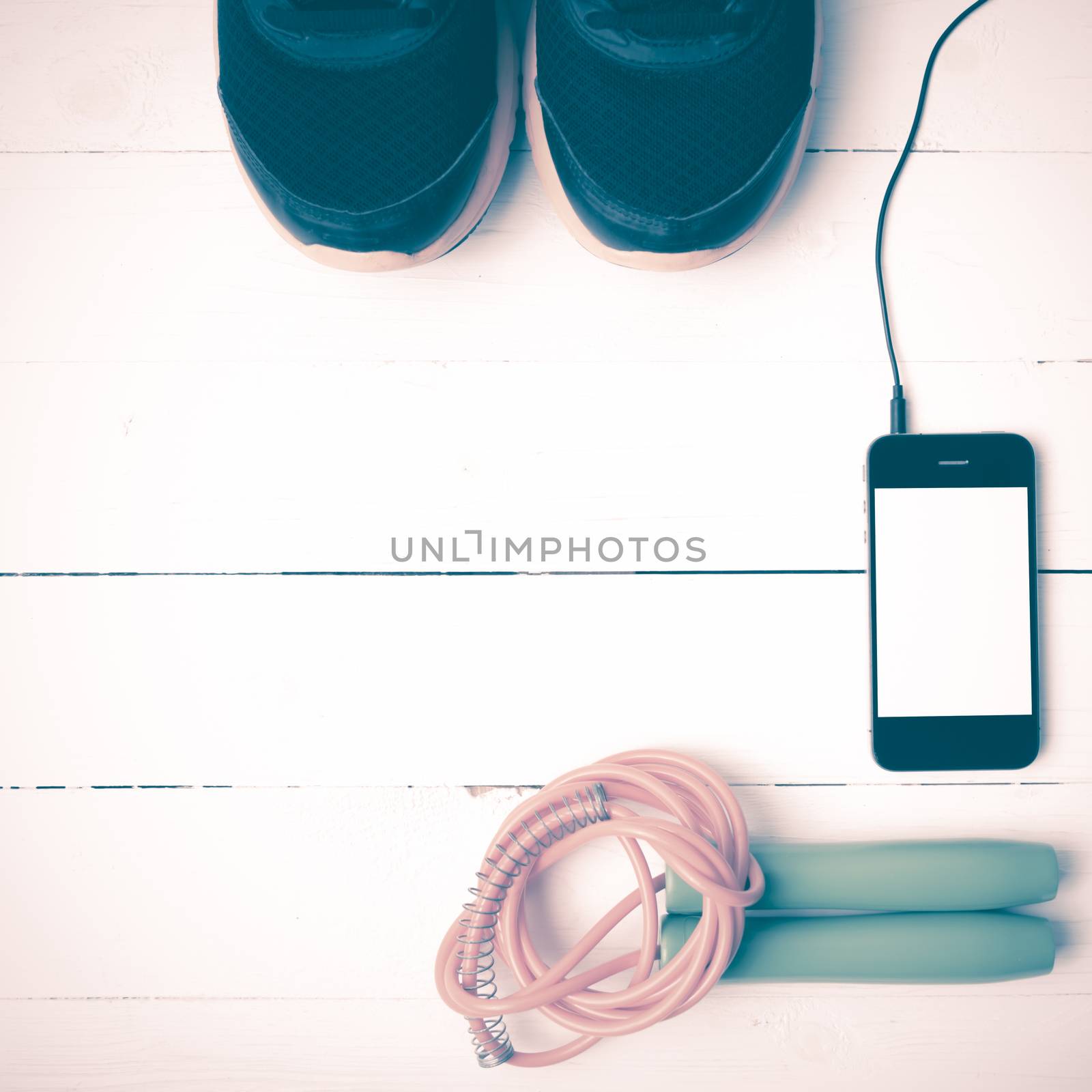 fitness equipment : running shoes,jumping rope and phone on white wood table vintage style