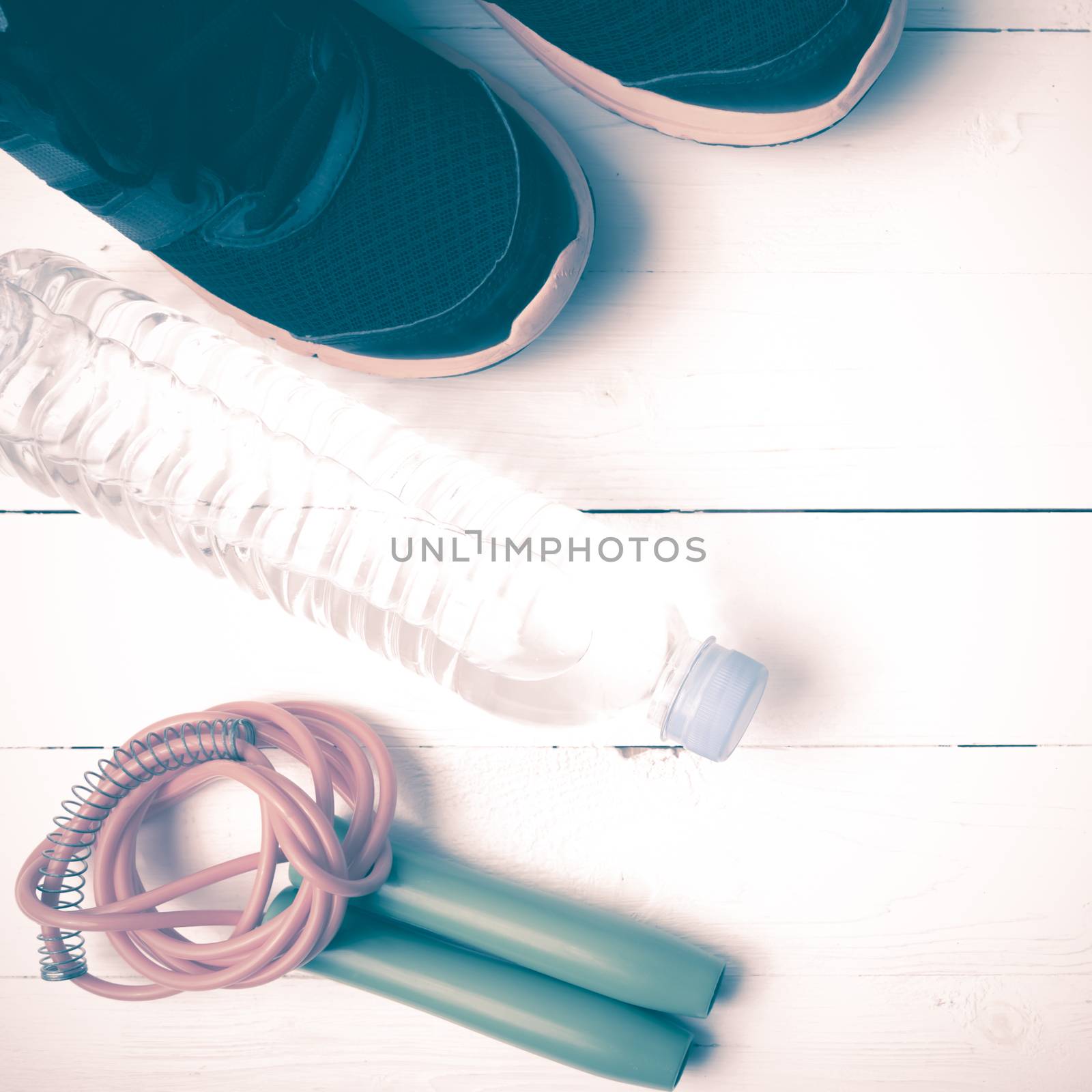 fitness equipment : running shoes,jumping rope,phone and water bottle on white wood table vintage style