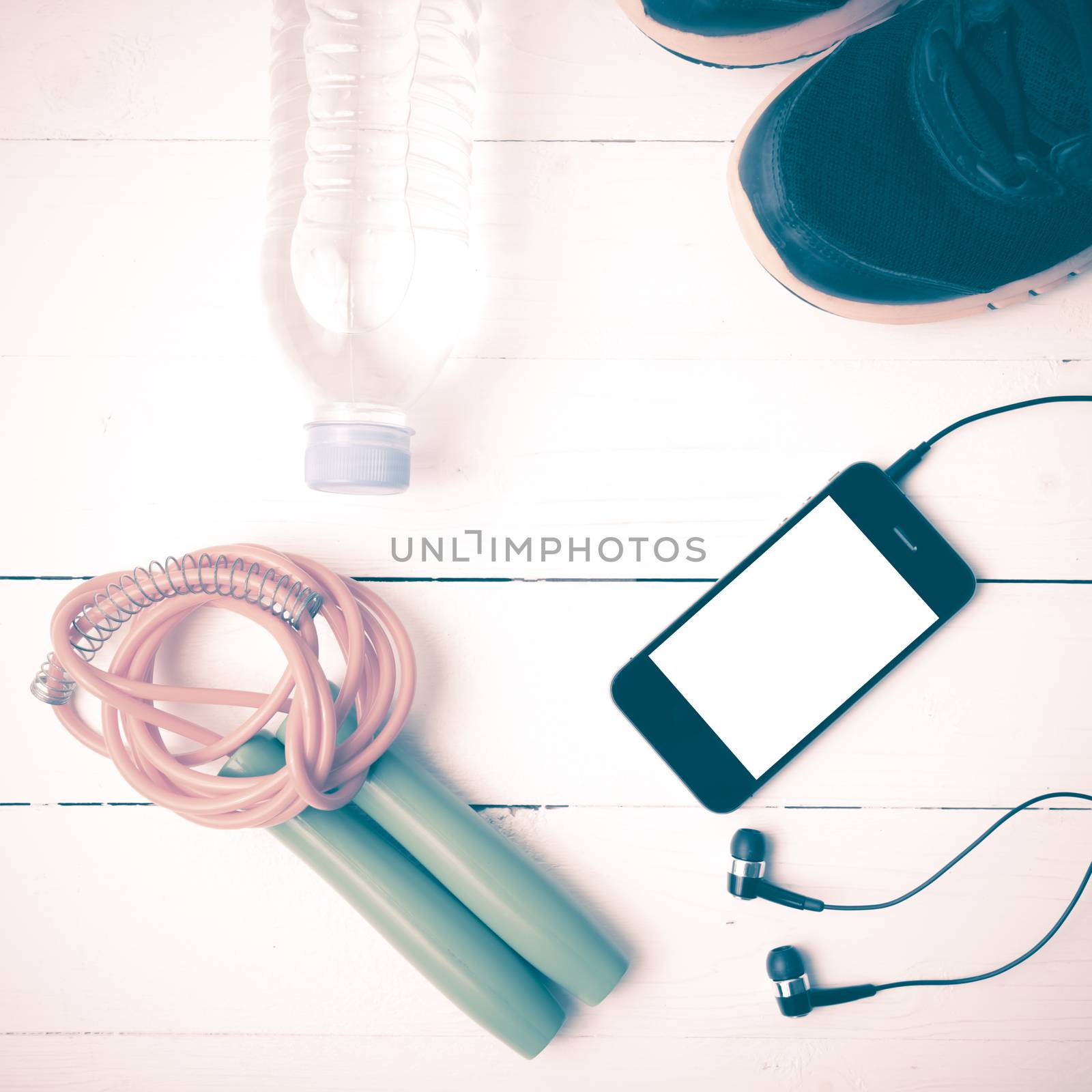 fitness equipment : running shoes,jumping rope,phone and water bottle on white wood table vintage style