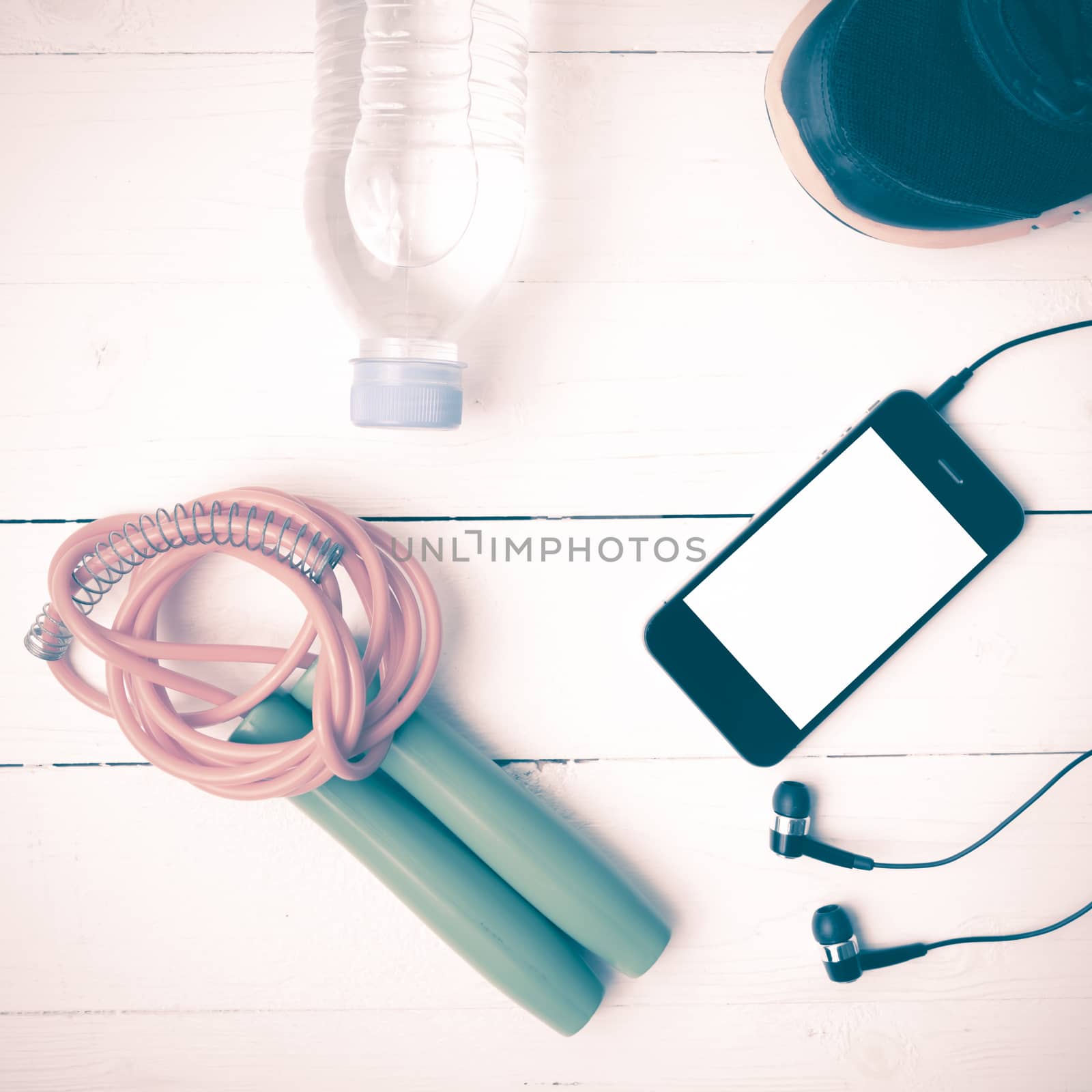 fitness equipment : running shoes,jumping rope,phone and water bottle on white wood table vintage style