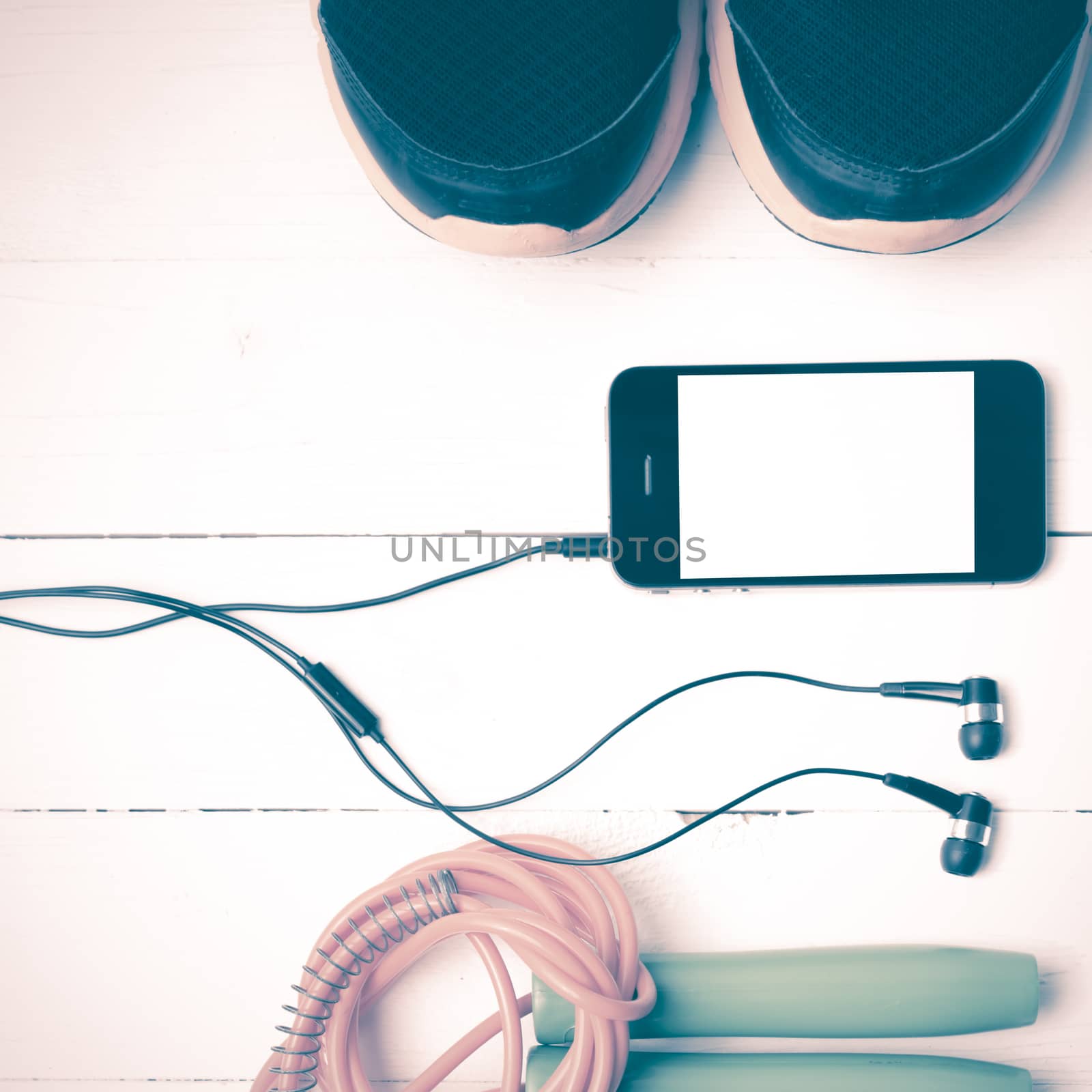 fitness equipment : running shoes,jumping rope and phone on white wood table vintage style