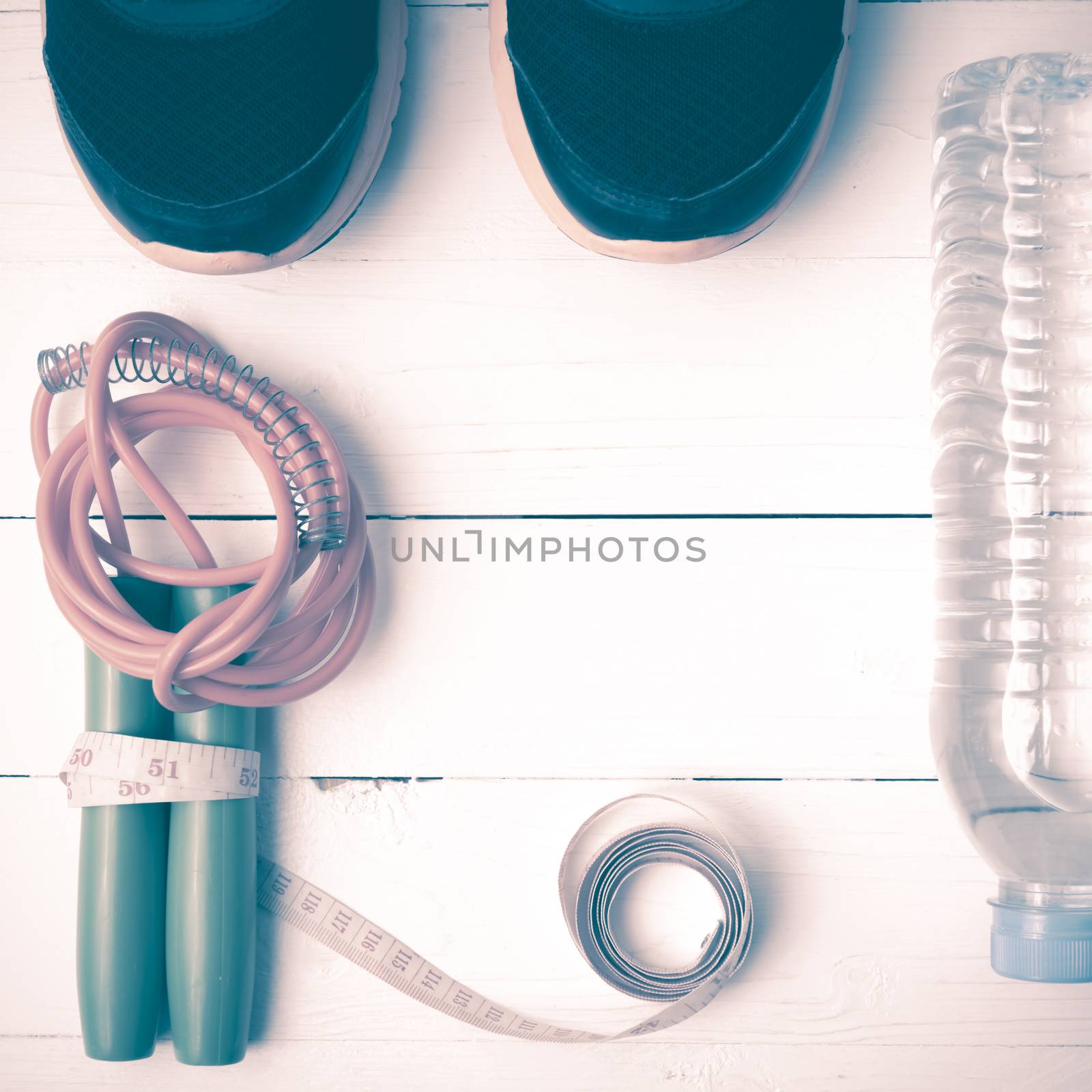 fitness equipment : running shoes,jumping rope,measuring tape and water bottle on white wood table vintage style