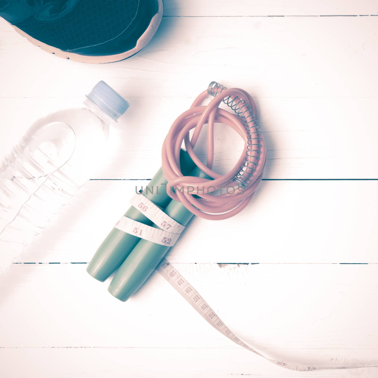 fitness equipment : running shoes,jumping rope,measuring tape and water bottle on white wood table vintage style