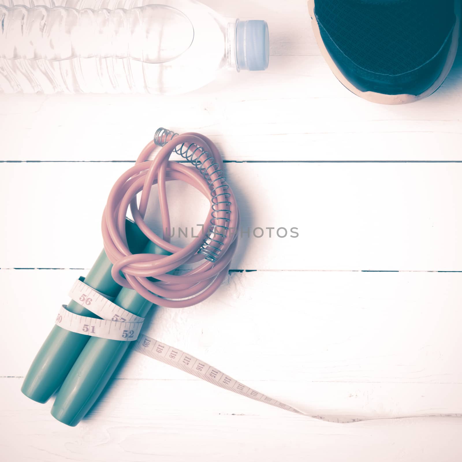 fitness equipment : running shoes,jumping rope,measuring tape and water bottle on white wood table vintage style