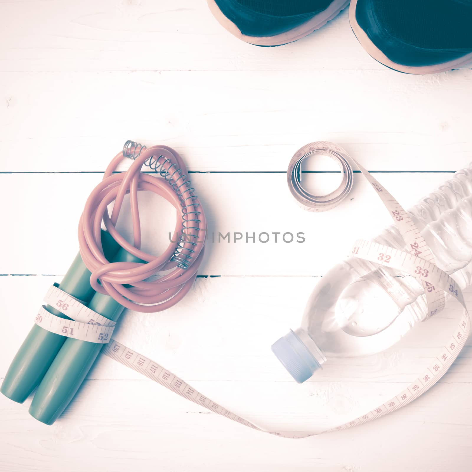 fitness equipment : running shoes,jumping rope,measuring tape and water bottle on white wood table vintage style