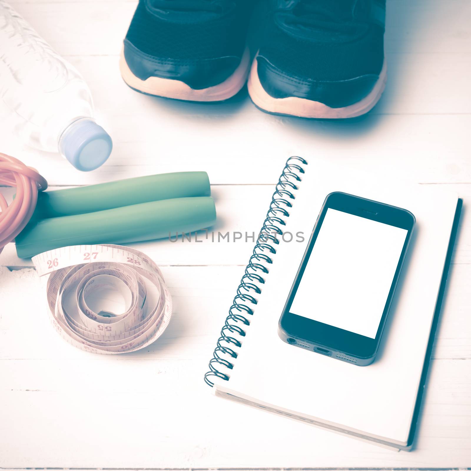 fitness equipment : running shoes,jumping rope,drinking water,notebook,measuring tape and phone on white wood table vintage style