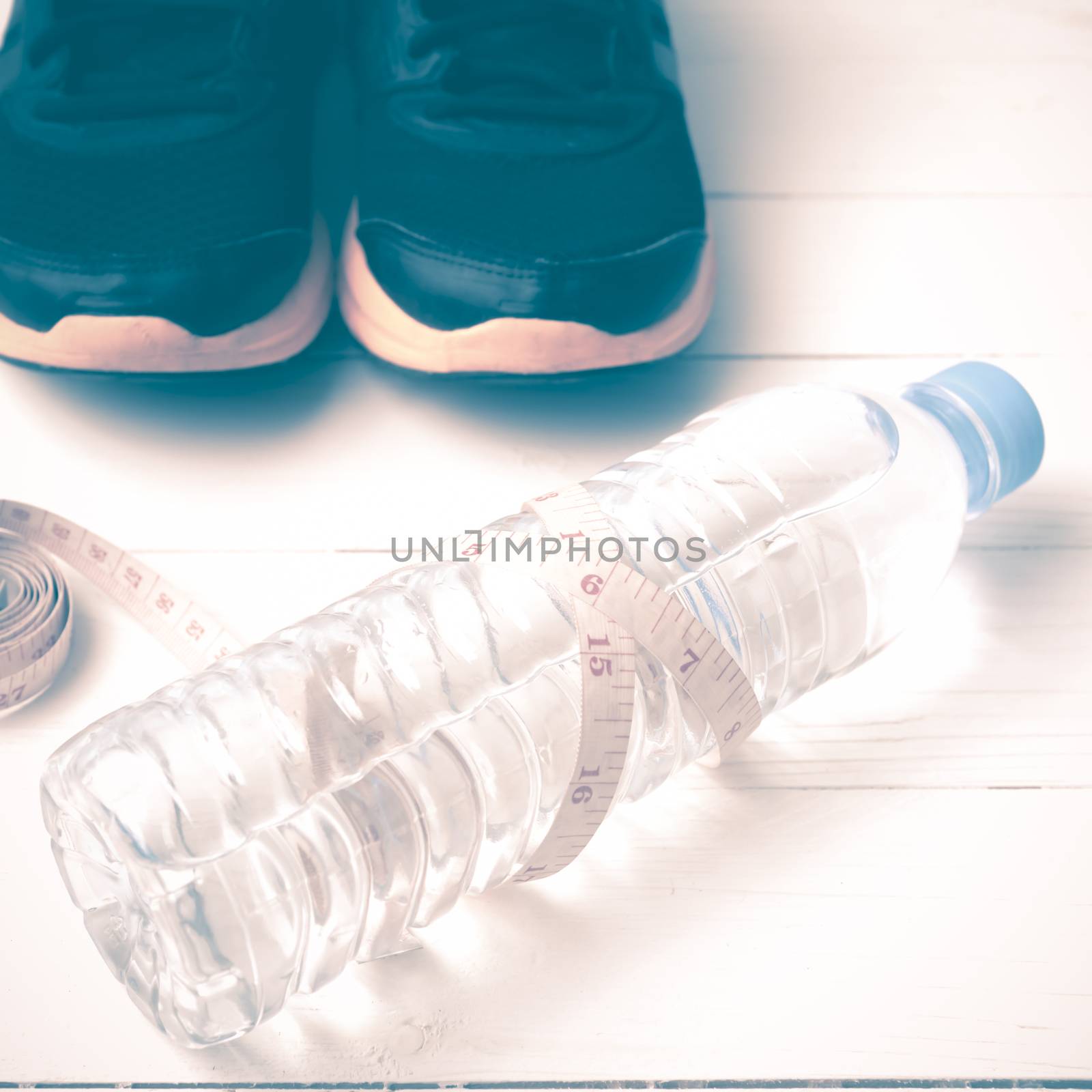 fitness equipment : running shoes,drinking water and measuring tape on white wood table vintage style