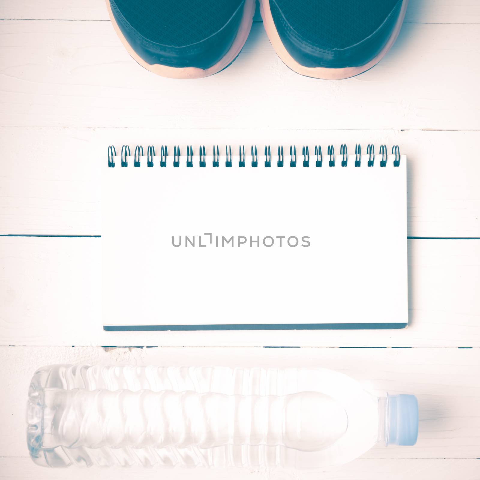 fitness equipment : running shoes,drinking water and notebook on white wood table vintage style