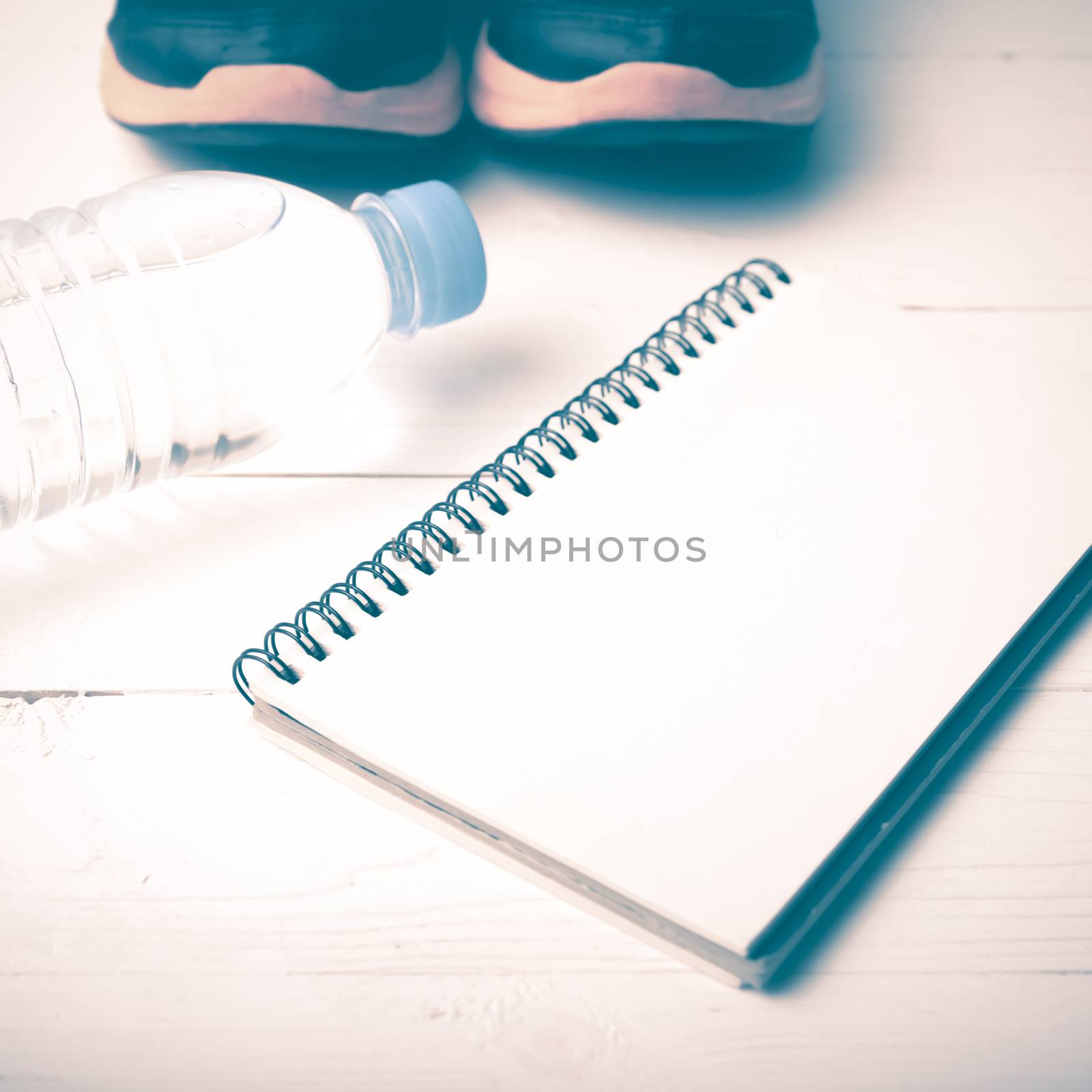 fitness equipment : running shoes,drinking water and notebook on white wood table vintage style