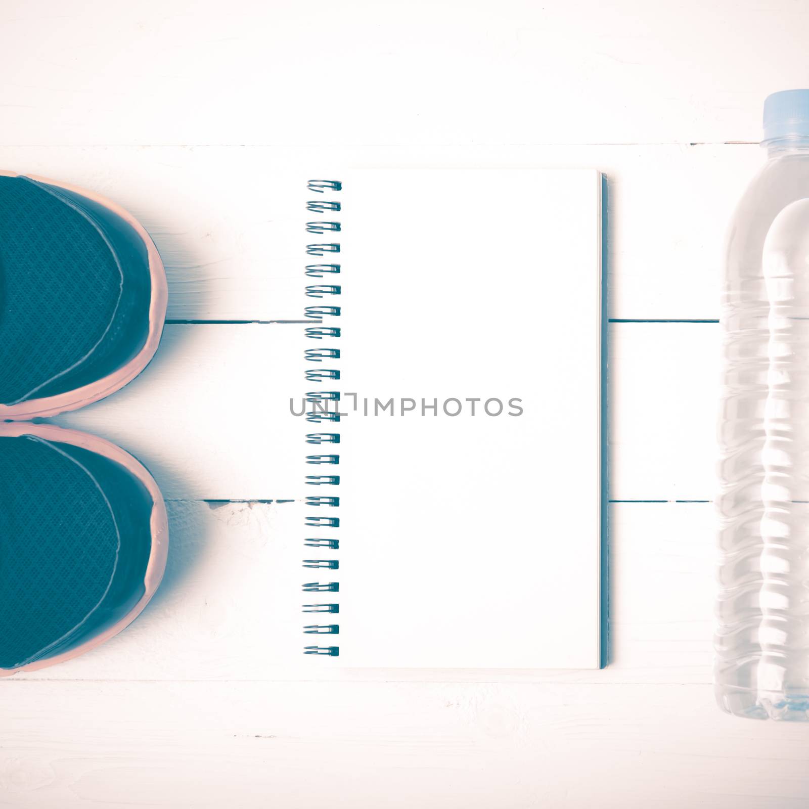 fitness equipment : running shoes,drinking water and notebook on white wood table vintage style