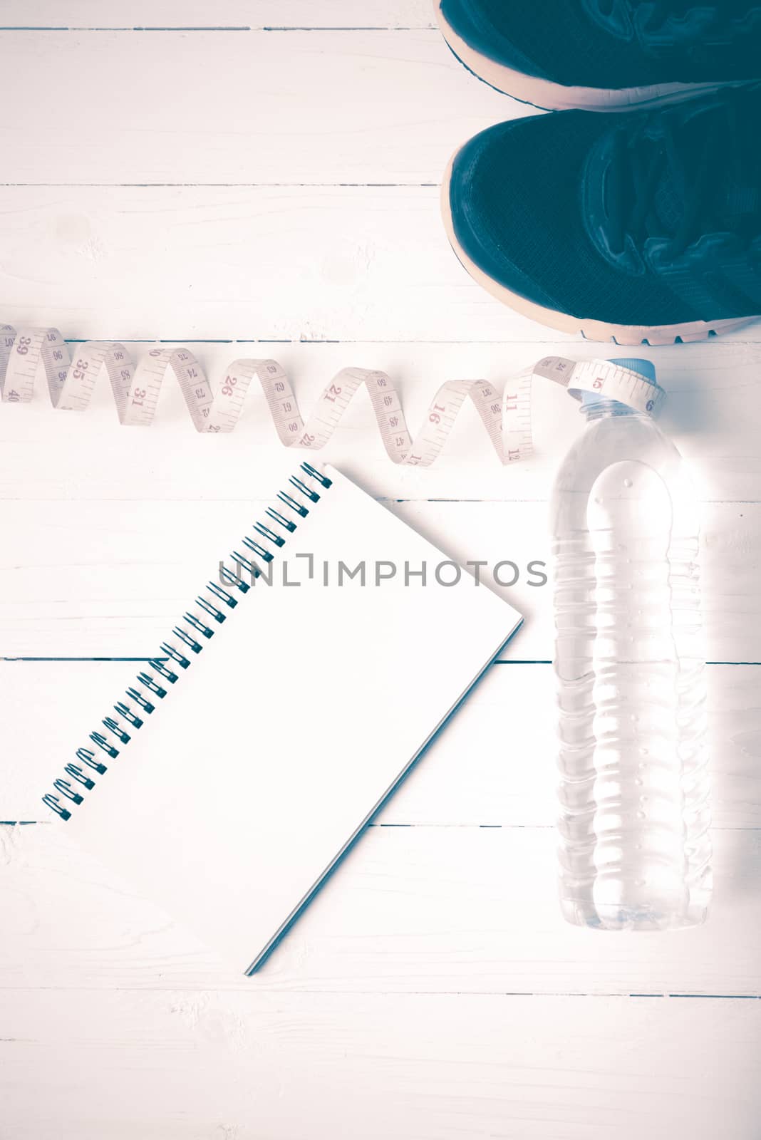 running shoes,measuring tape,drinking water and notebook on white wood table vintage style