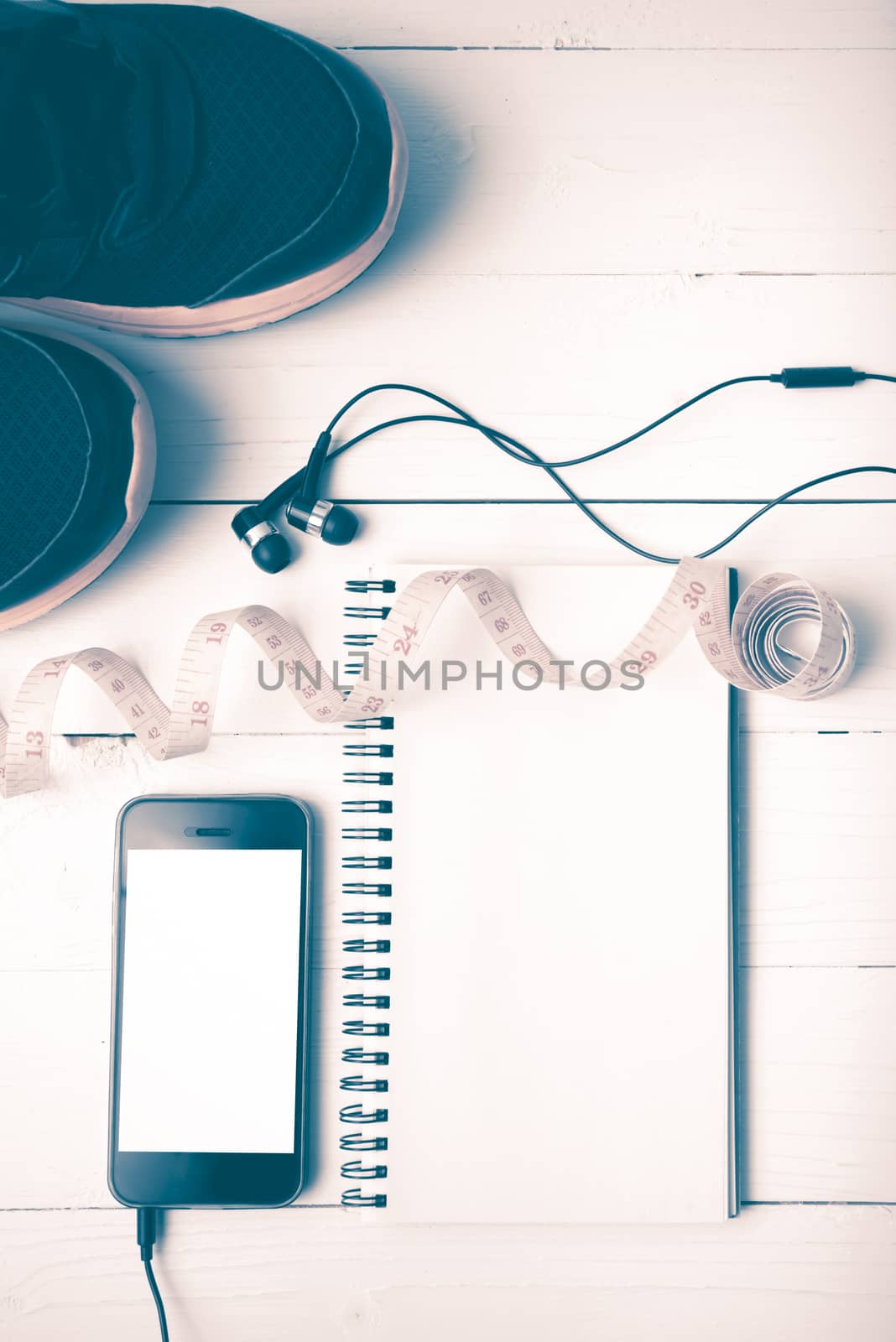 running shoes,measuring tape,notebook and phone on white wood table vintage style