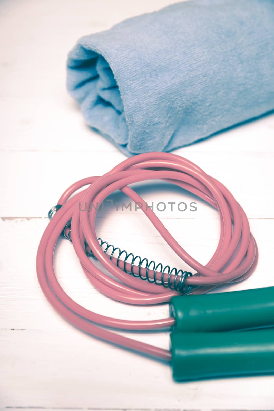 fitness equipment:blue towel,jumping rope on white wood table vintage style