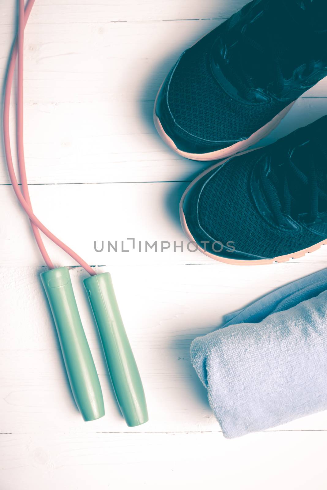 fitness equipment:blue towel,jumping rope and running shoes on white wood table vintage style