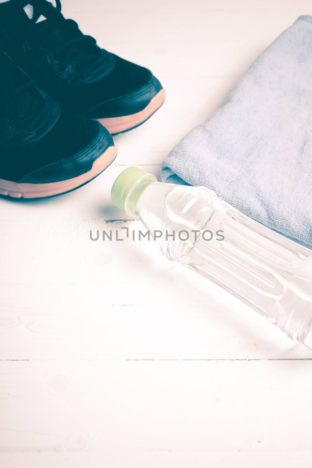 fitness equipment:blue towel,drinking water and running shoes on white wood table vintage style