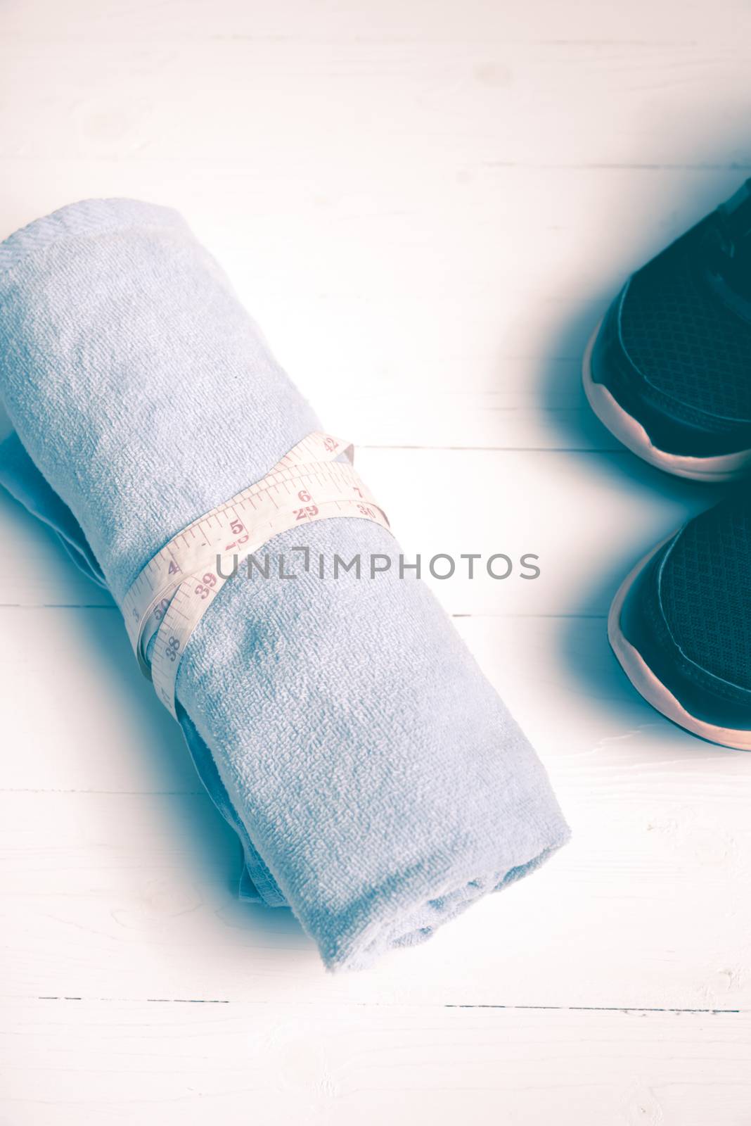 fitness equipment : running shoes,blue towel and measuring tape on white wood table vintage style