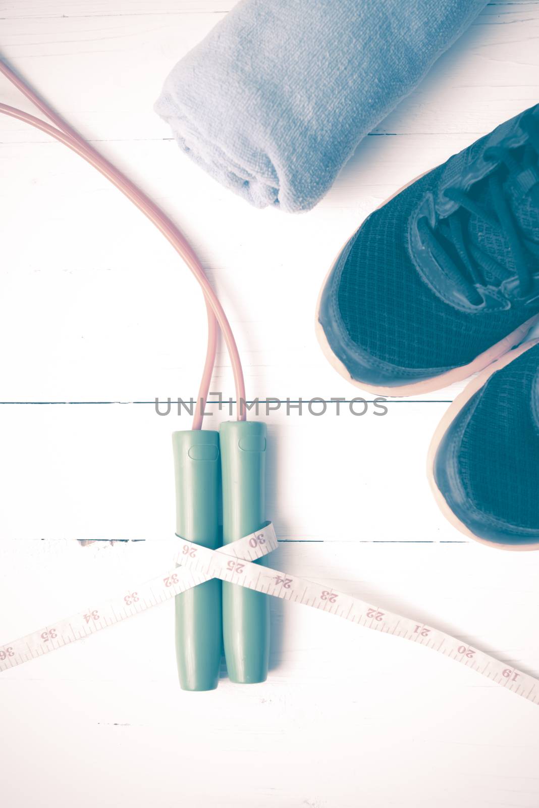 fitness equipment : running shoes,towel,jumping rope and measuring tape on white wood table vintage style