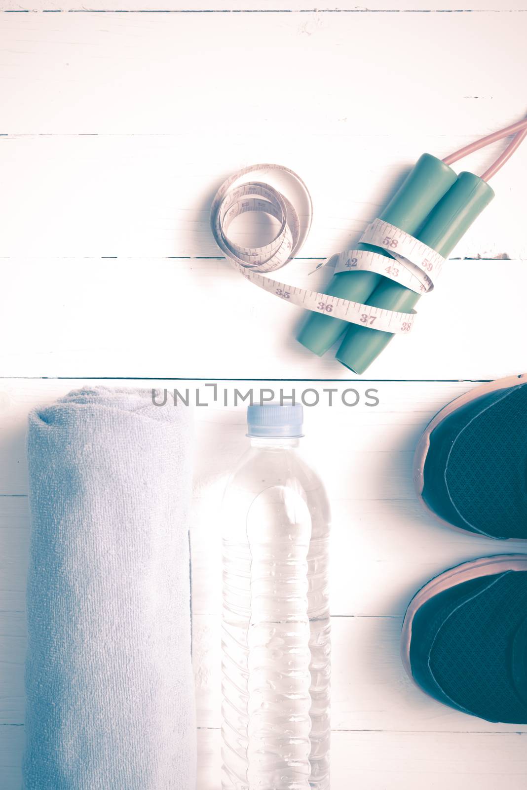 fitness equipment : running shoes,towel,jumping rope,water bottle and measuring tape on white wood table vintage style