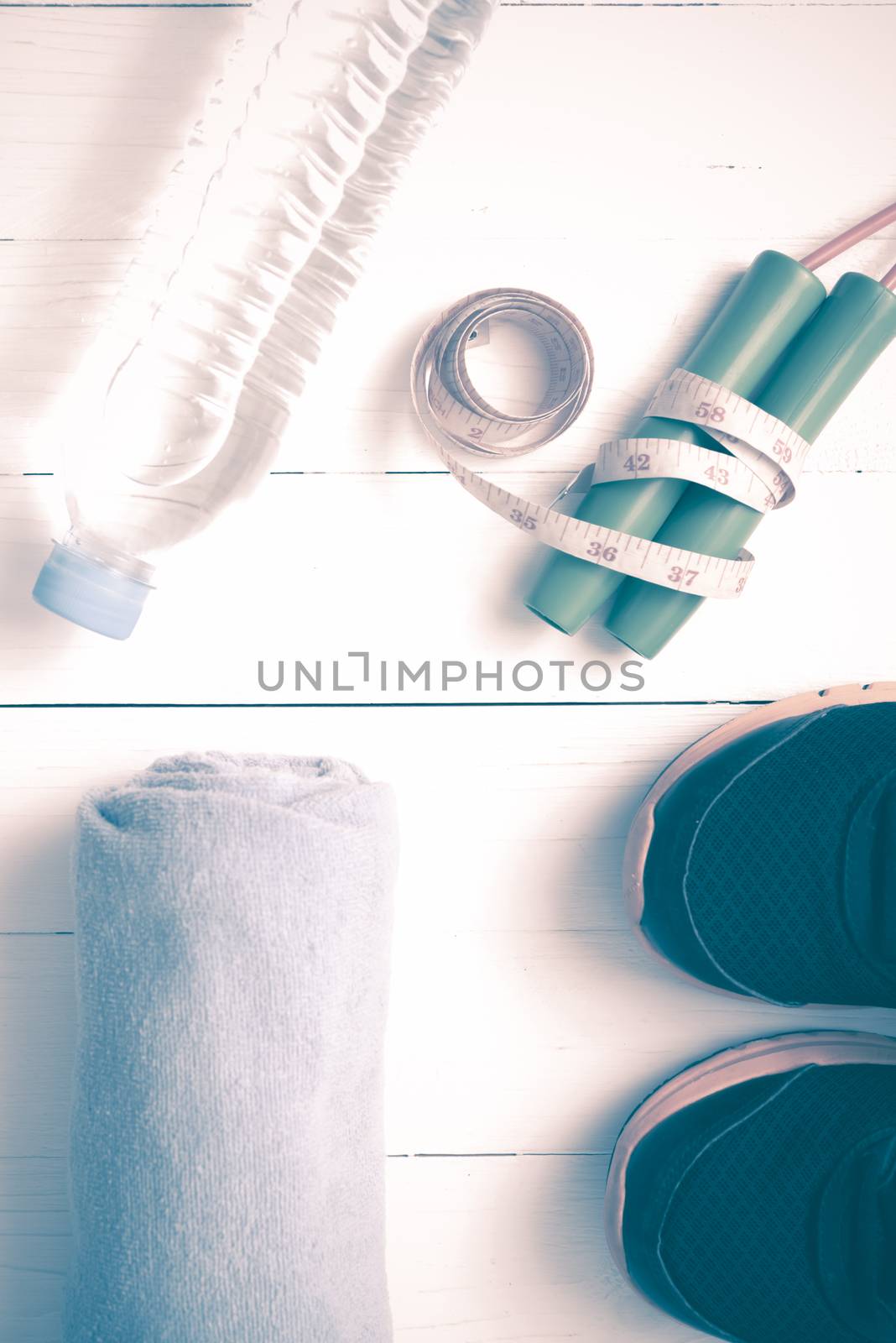 fitness equipment : running shoes,towel,jumping rope,water bottle and measuring tape on white wood table vintage style