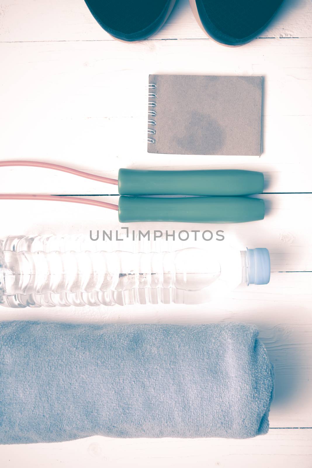 fitness equipment : running shoes,towel,jumping rope,water bottle and notepad on white wood table vintage style