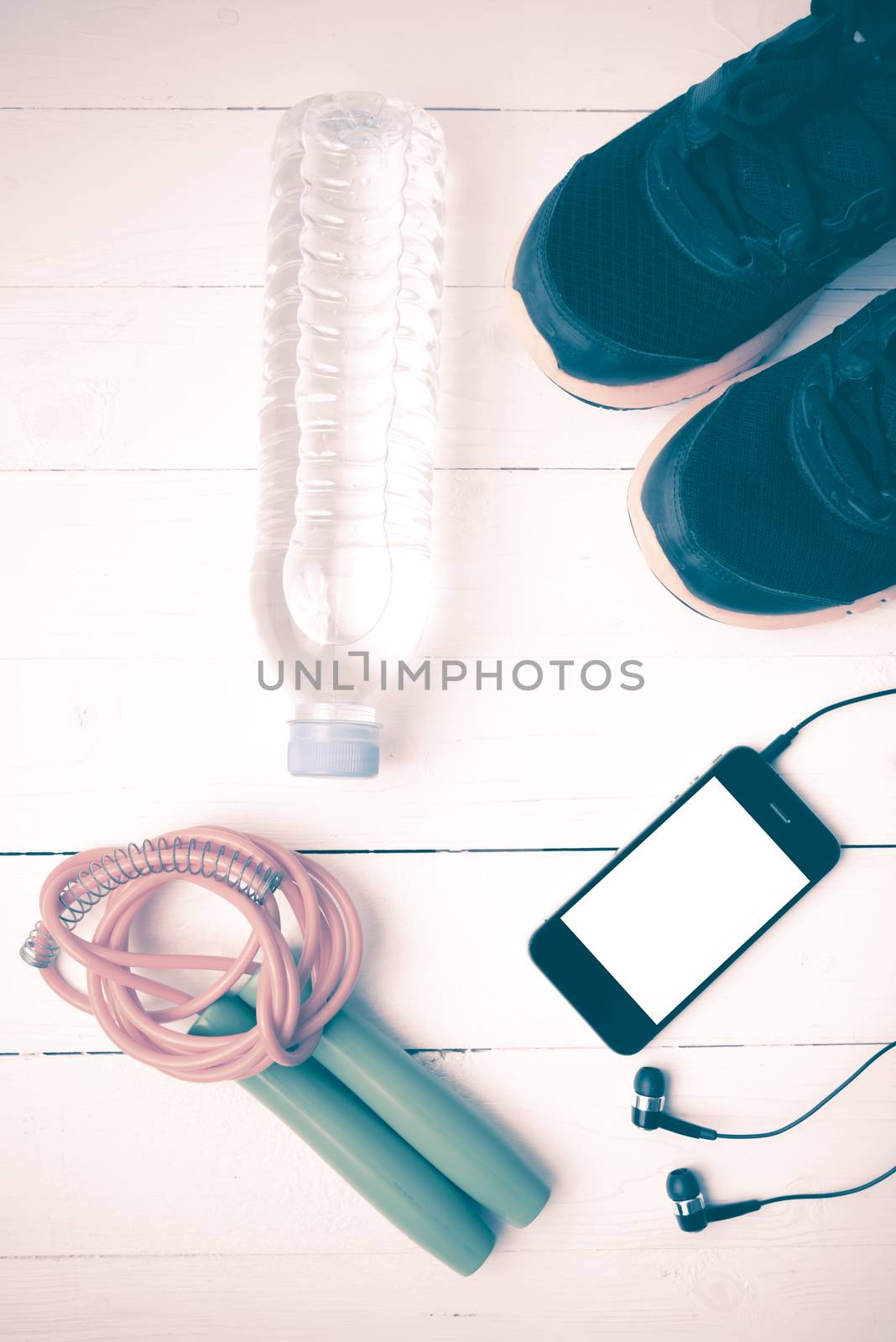 fitness equipment : running shoes,jumping rope,phone and water bottle on white wood table vintage style