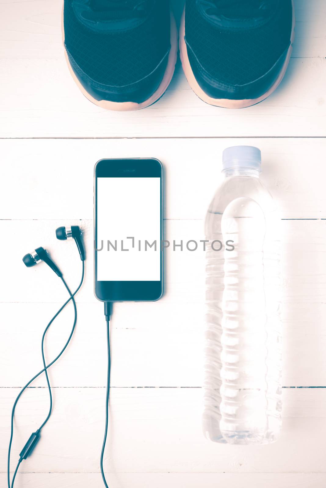 fitness equipment : running shoes,drinking water and phone on white wood table vintage style