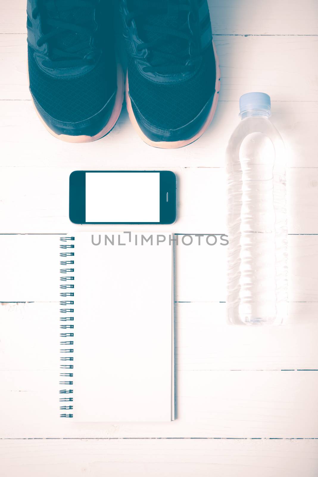 fitness equipment : running shoes,drinking water,notebook and phone on white wood table vintage style