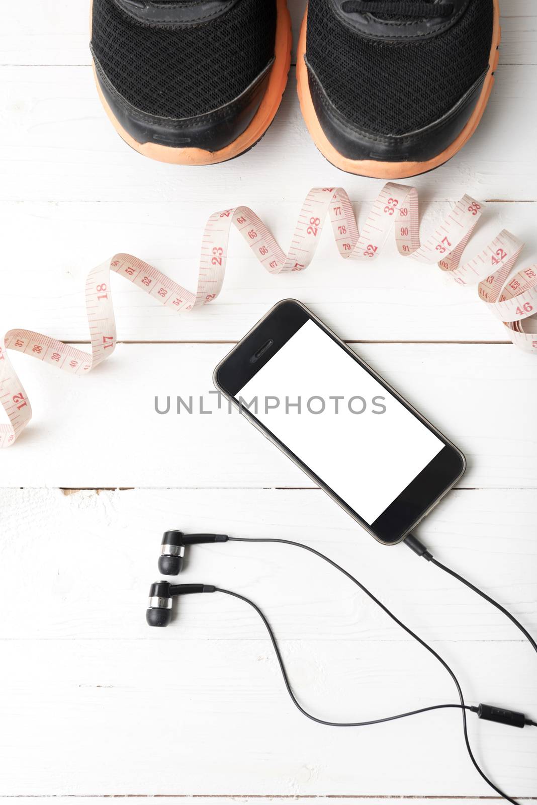 running shoes,measuring tape and phone on white wood table