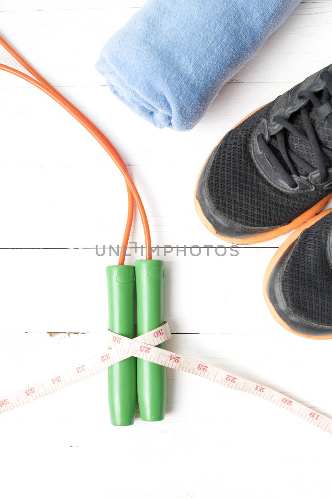 fitness equipment : running shoes,towel,jumping rope and measuring tape on white wood table