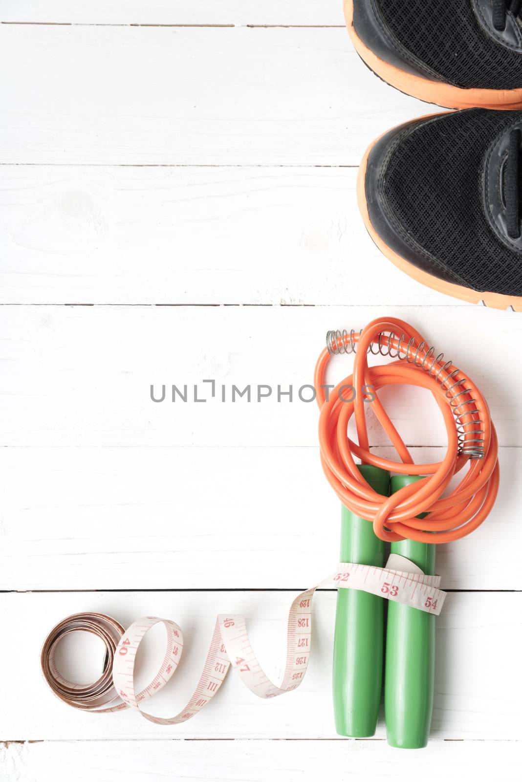 fitness equipment : running shoes,jumping rope and measuring tape on white wood table