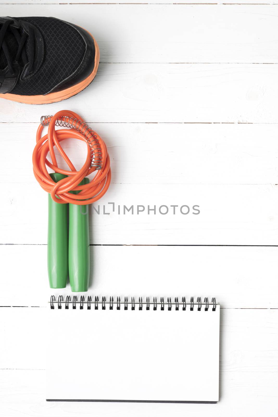 fitness equipment : running shoes,jumping rope and notepad on white wood table