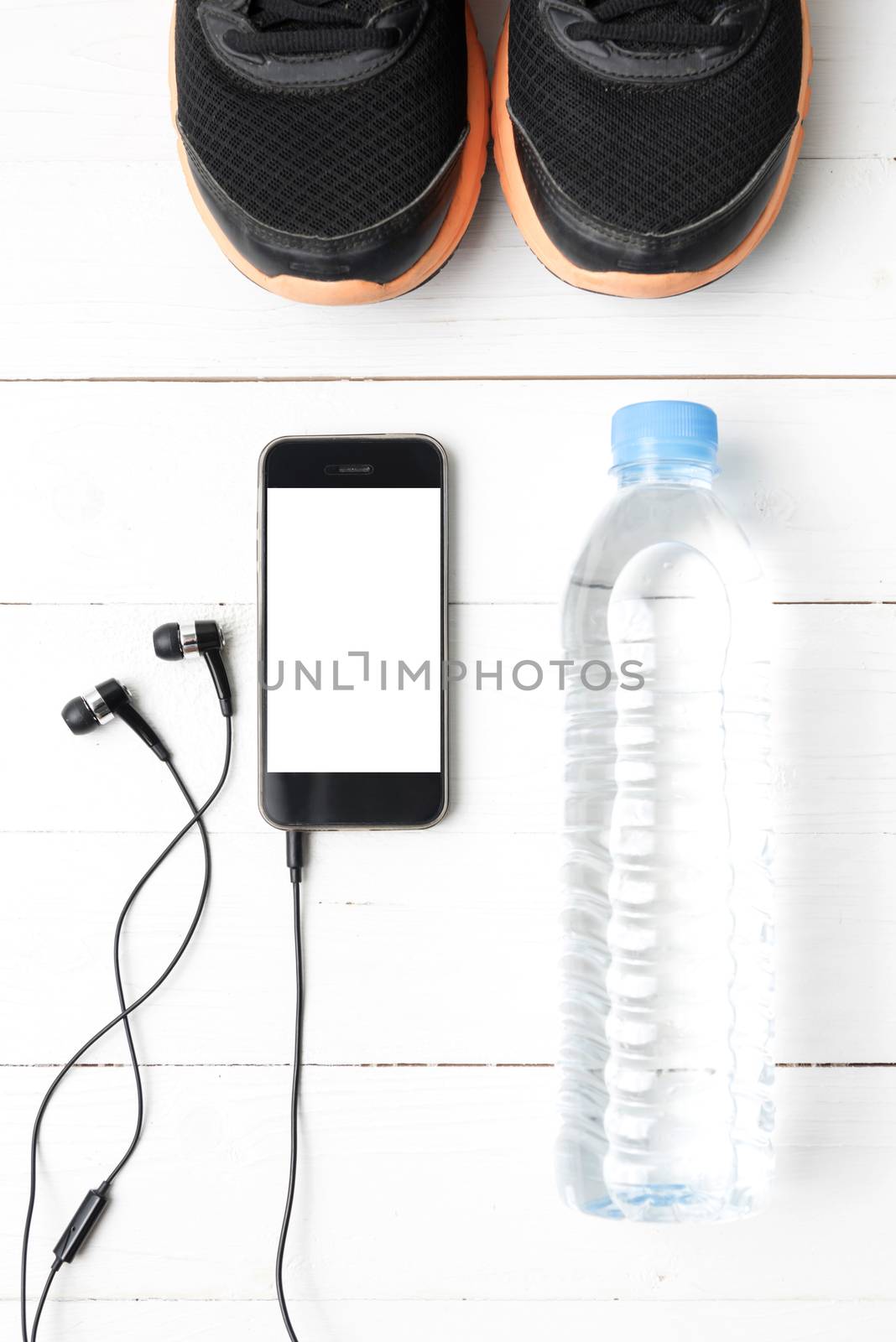 fitness equipment : running shoes,drinking water and phone on white wood table