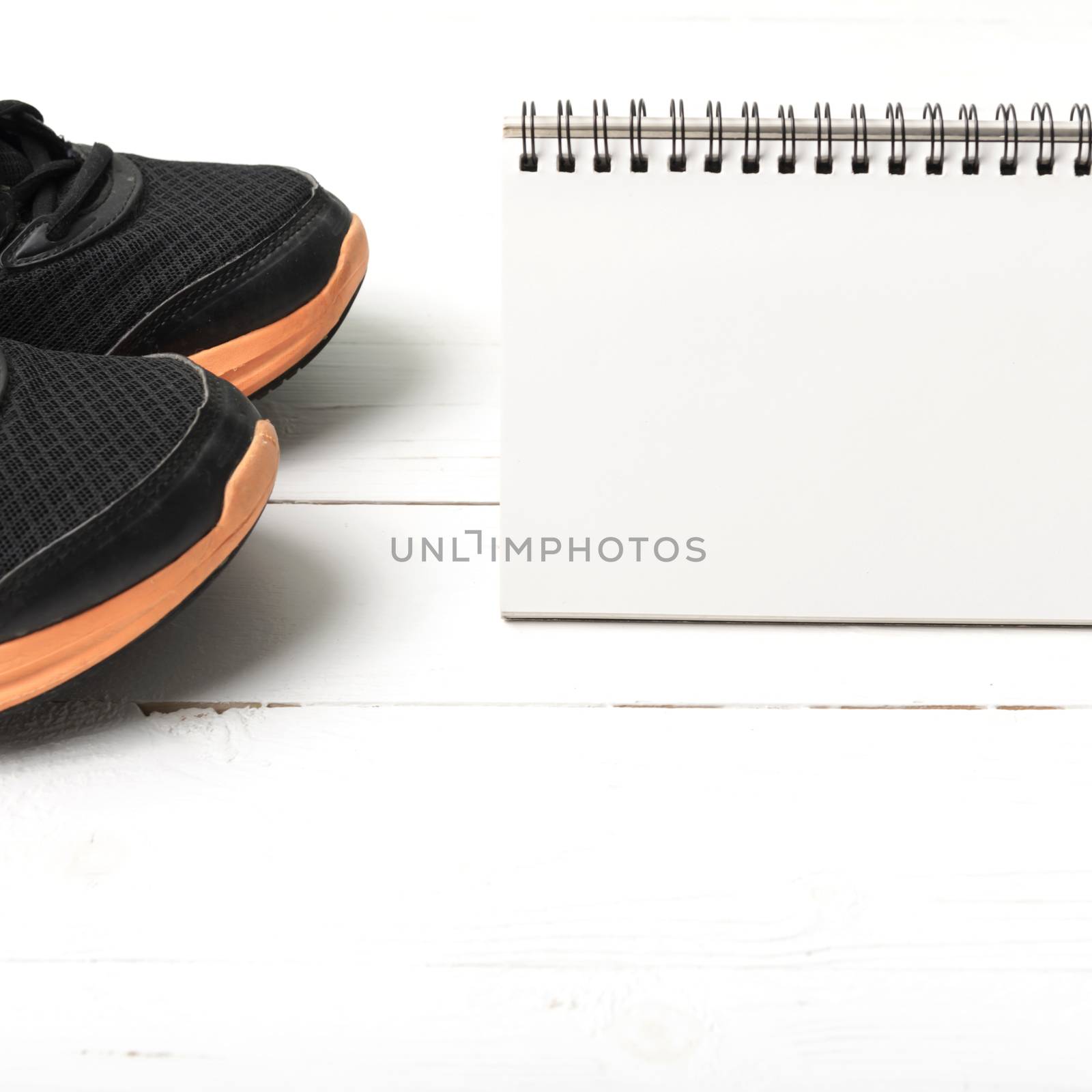 running shoes and notepad on white wood table