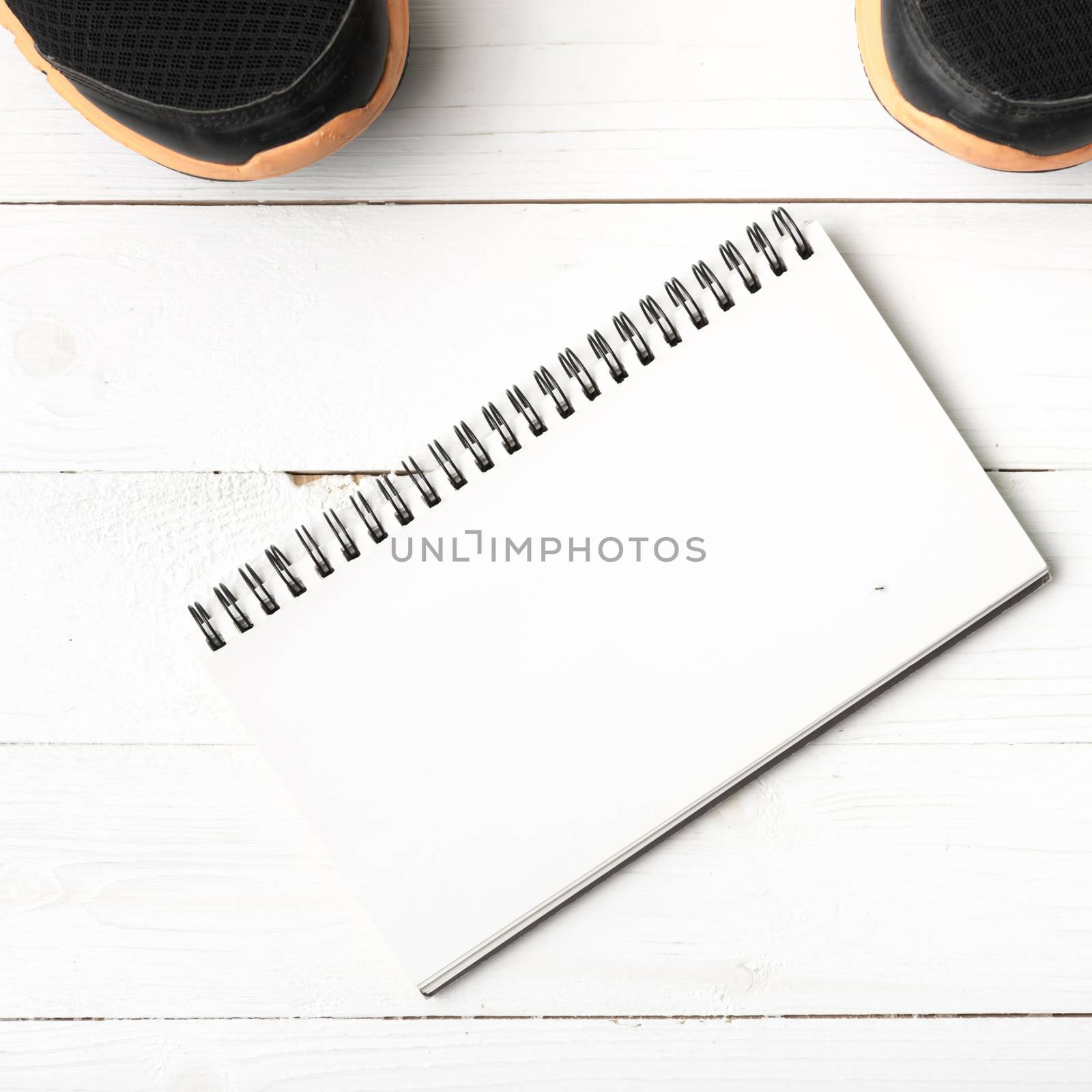 running shoes and notepad on white wood table