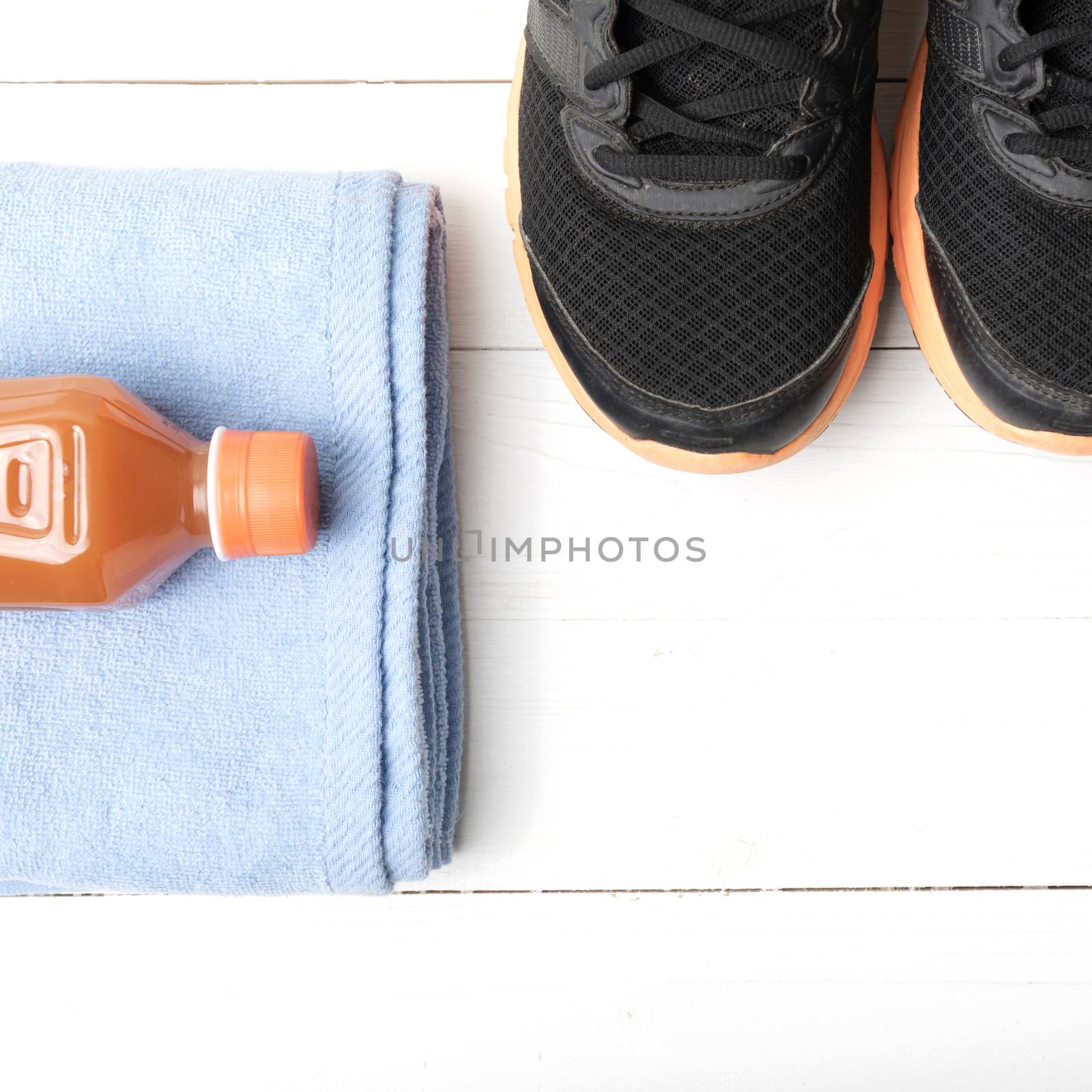 running shoes,towel and orange juice on white wood table