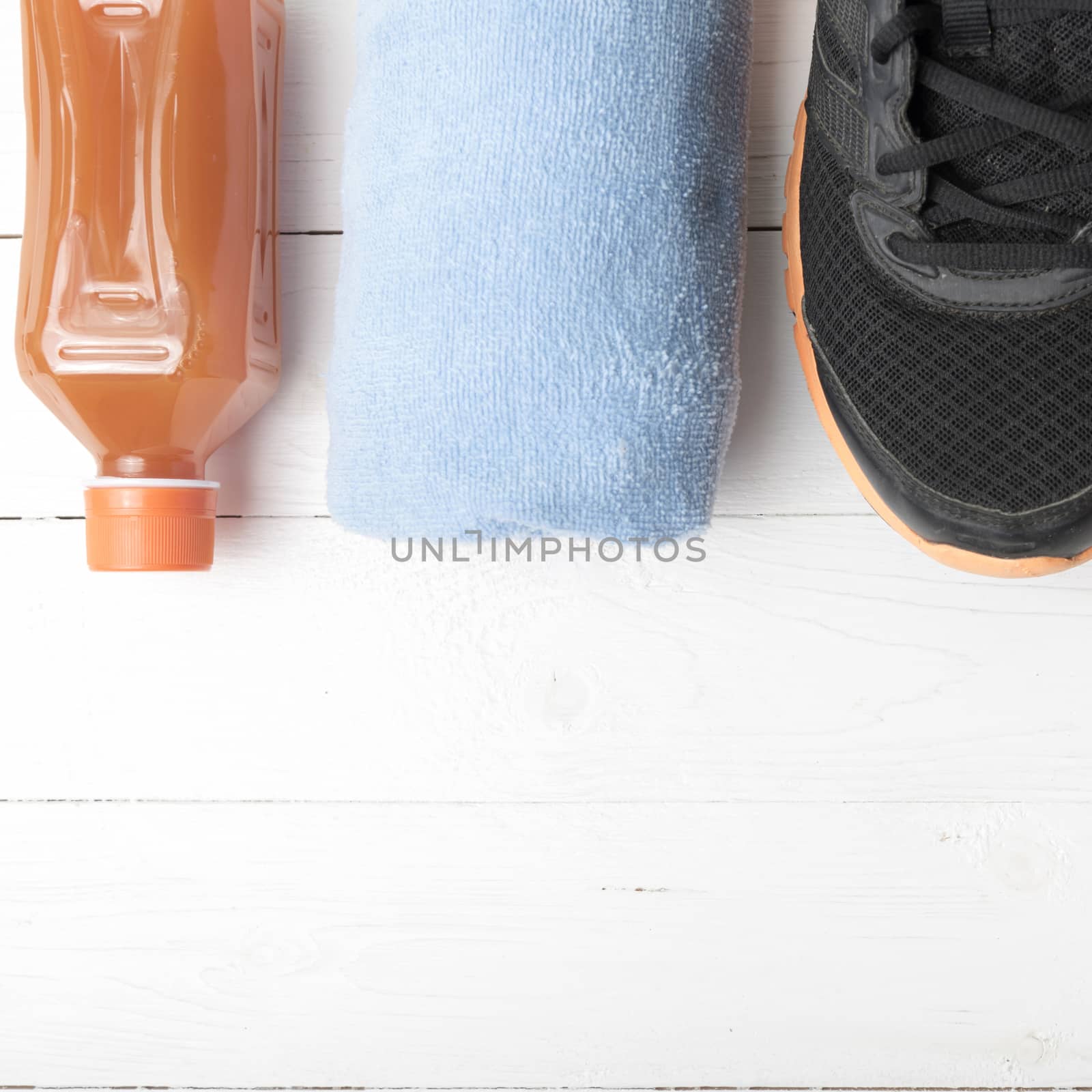 running shoes,towel and orange juice on white wood table