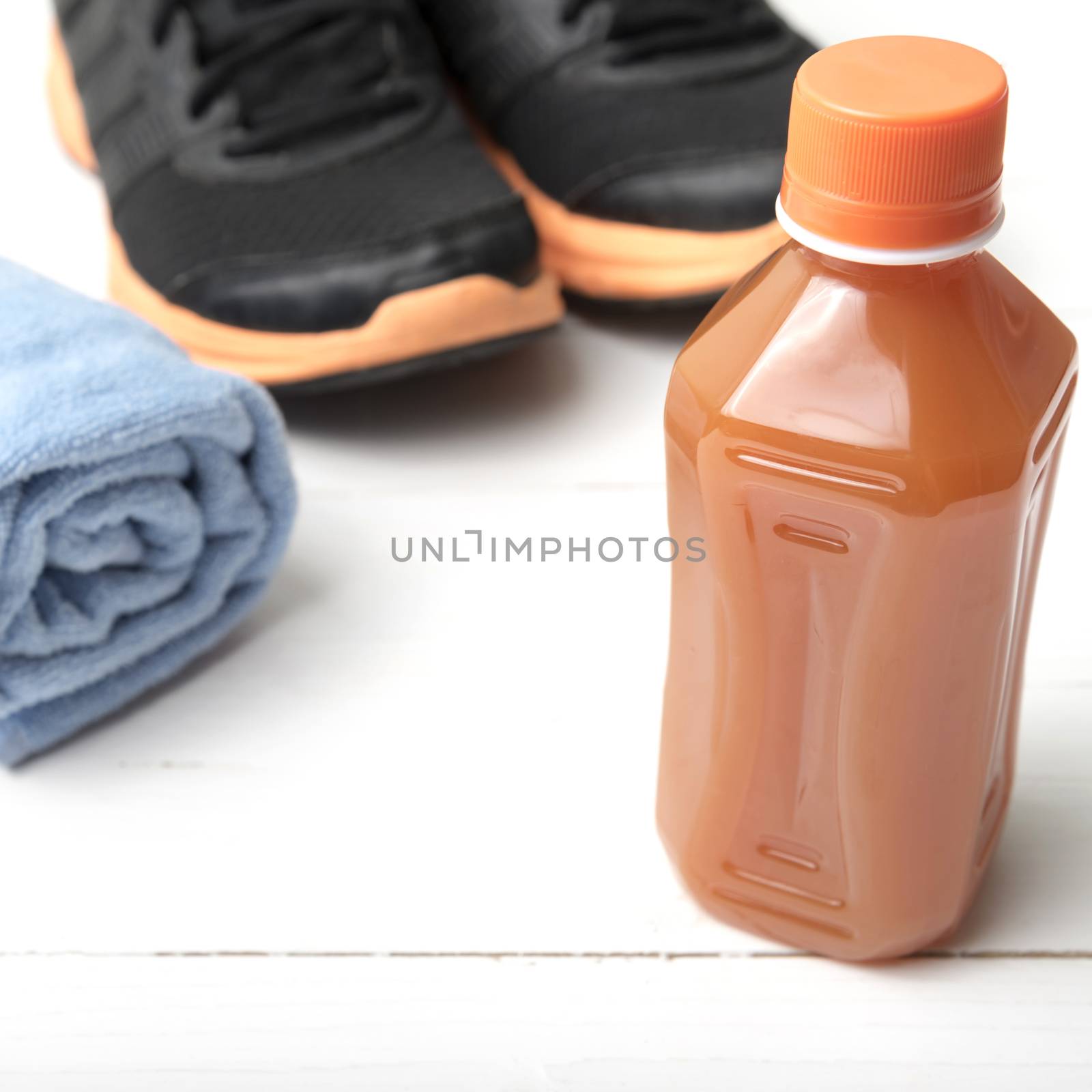 running shoes,towel and orange juice on white wood table