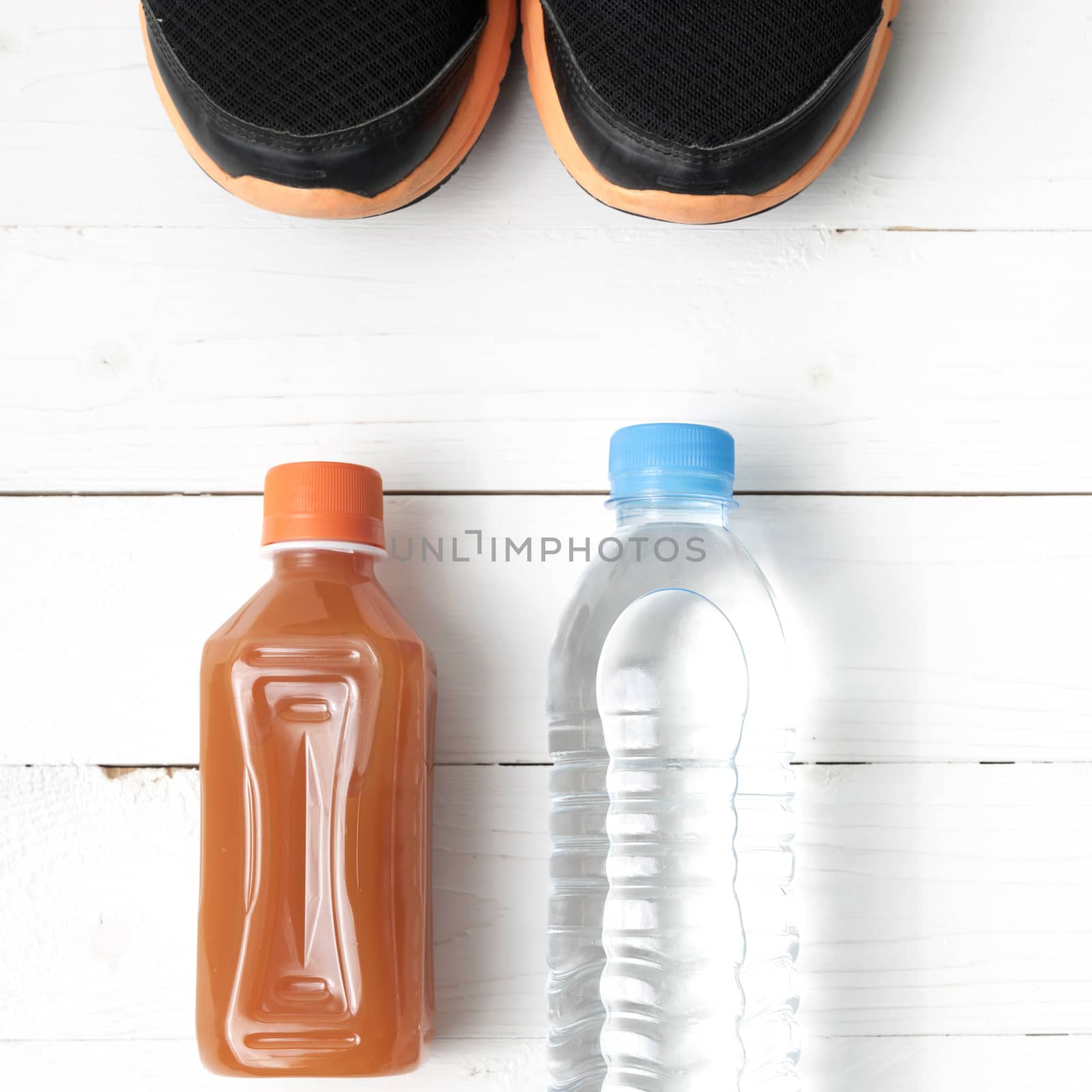 running shoes,drinking water and orange juice on white wood table