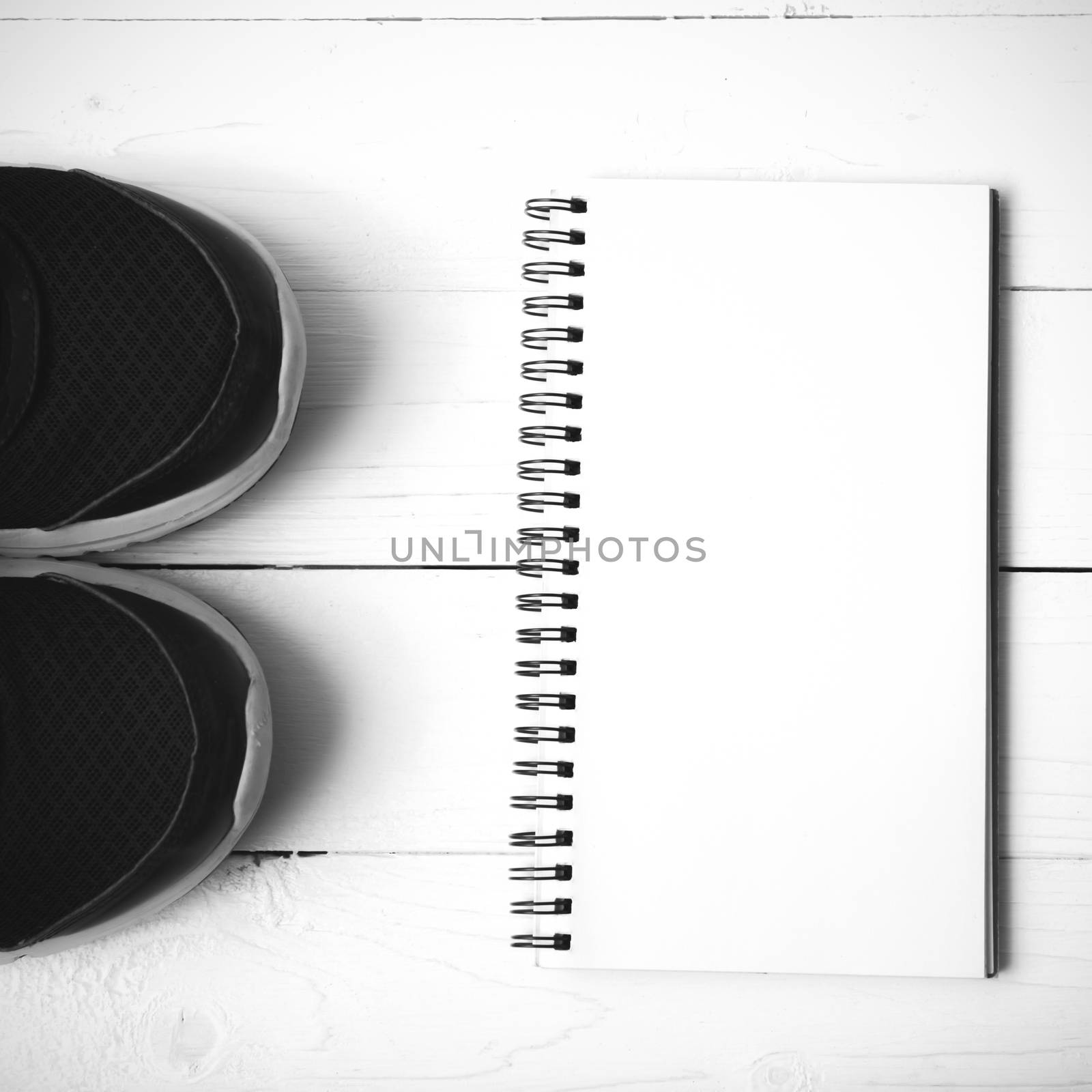 running shoes and notepad on white wood table black and white tone color style