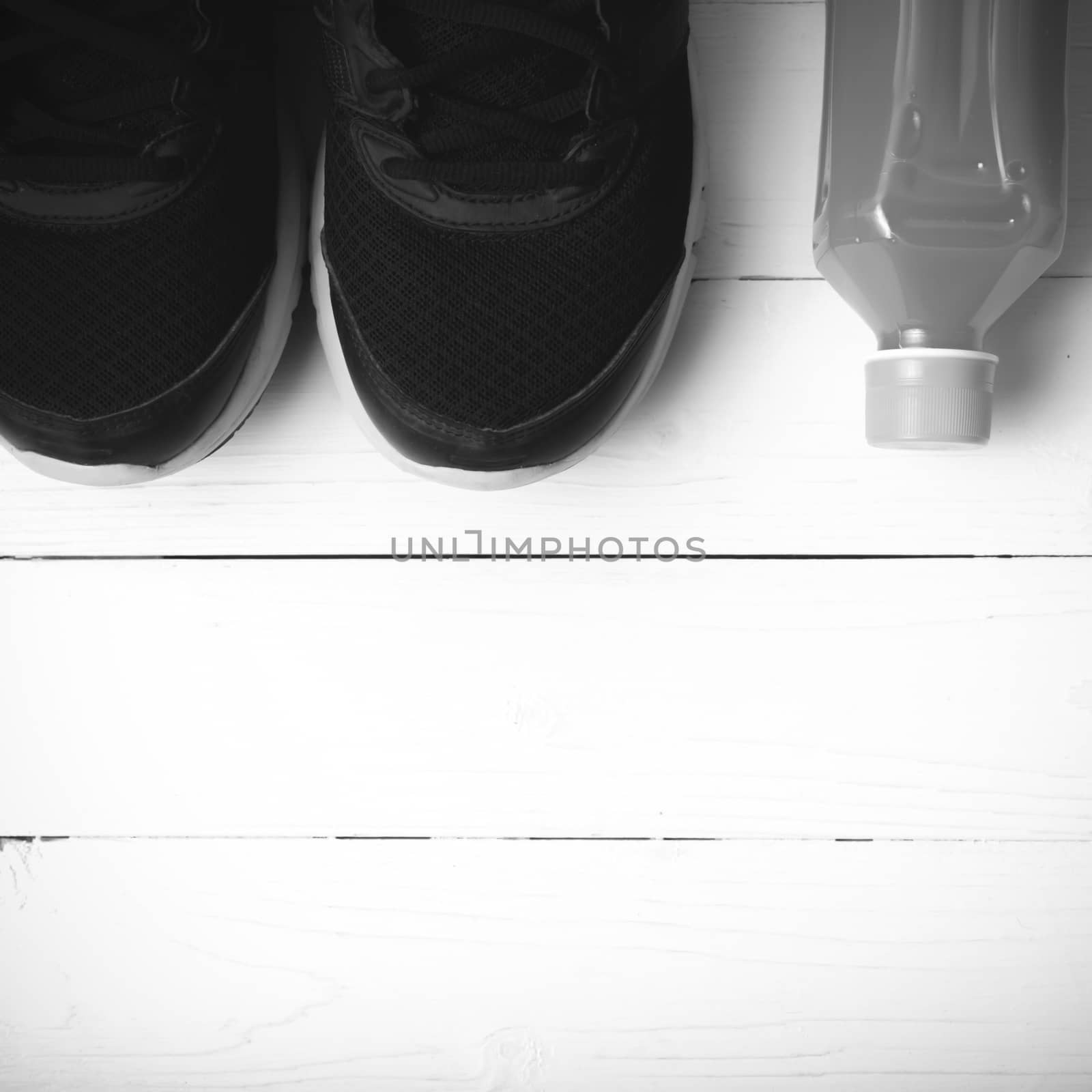 running shoes and orange juice on white wood table black and white tone color style