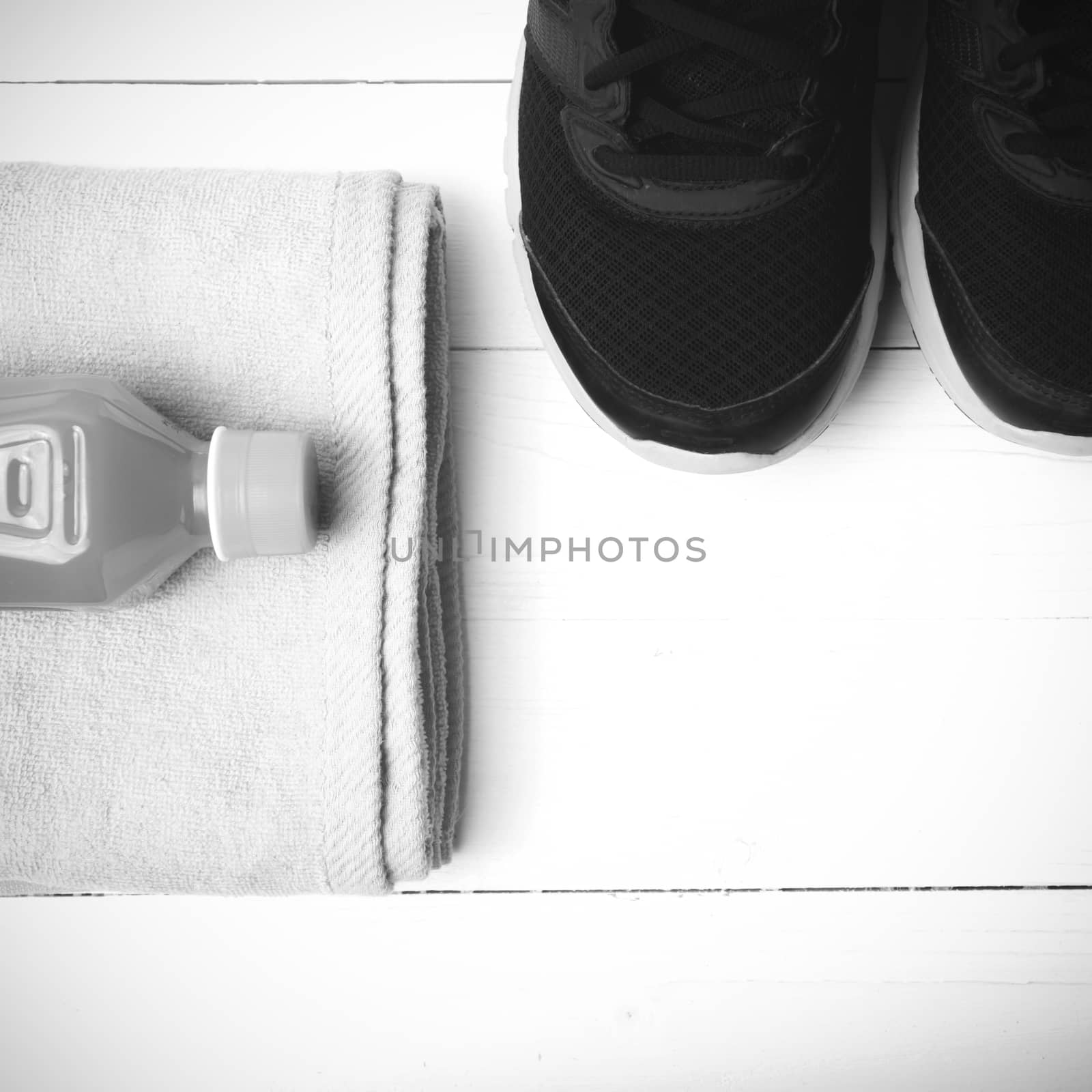 running shoes,towel and orange juice on white wood table black and white tone color style