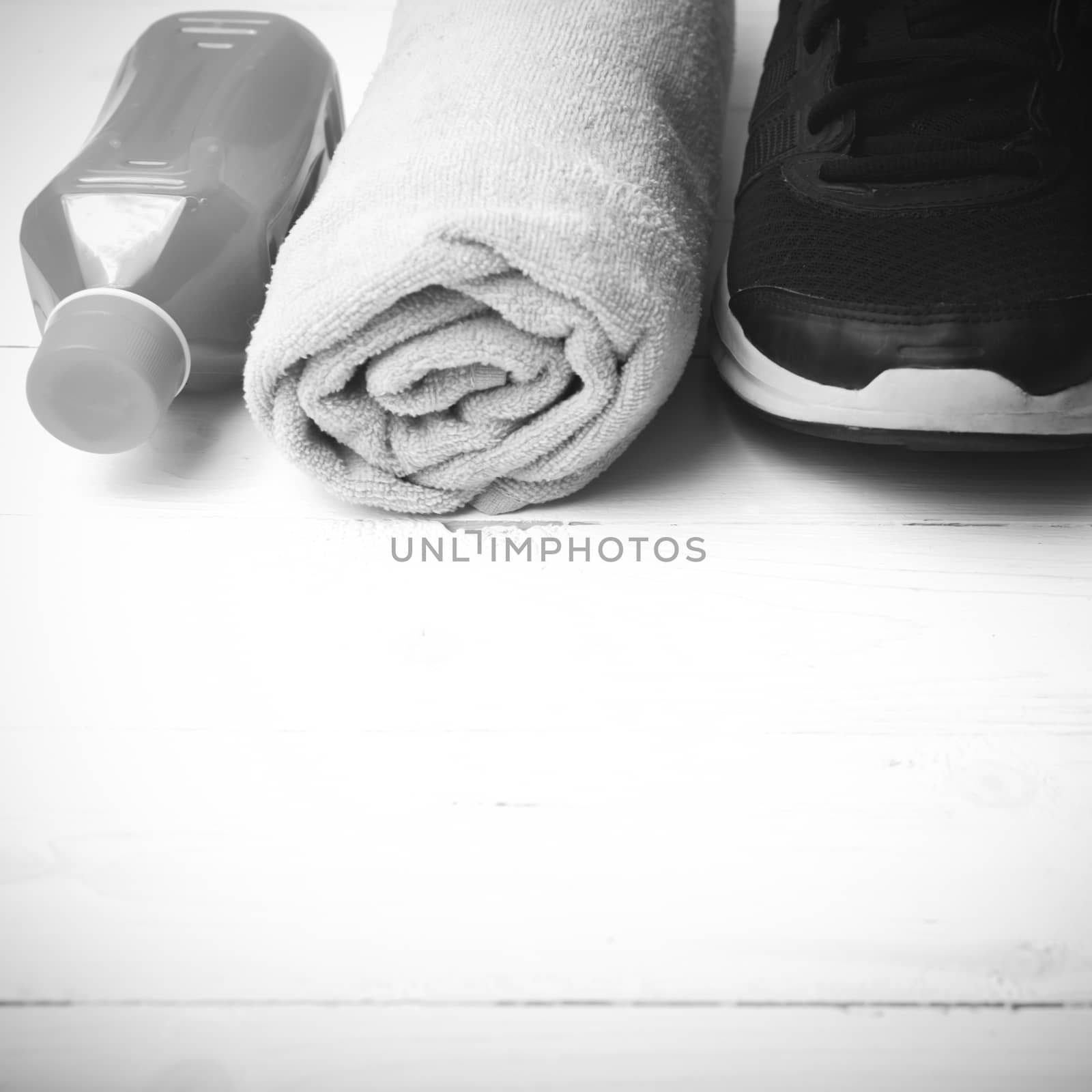 running shoes,towel and orange juice on white wood table black and white tone color style