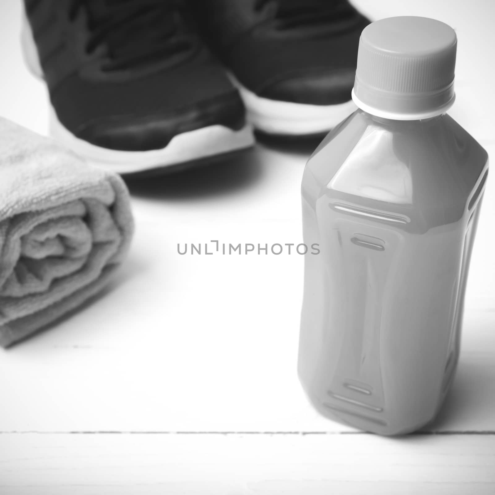 running shoes,towel and orange juice on white wood table black and white tone color style